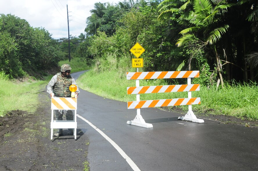 Senior Airman Rory Valle, 291st Combat Communications Squadron, Hawaii Air National Guard, places road barriers to prevent traffic to the lava flow while on patrol, Hawaii, Oct. 30, 2014. Hawaii Army and Air Nation Guardsmen were called to support Civil Defense authorities as the Puna lava flow makes it way towards the highway and local homes. (U.S. Army National Guard photo by Staff Sgt. Katie Gray/Released)


