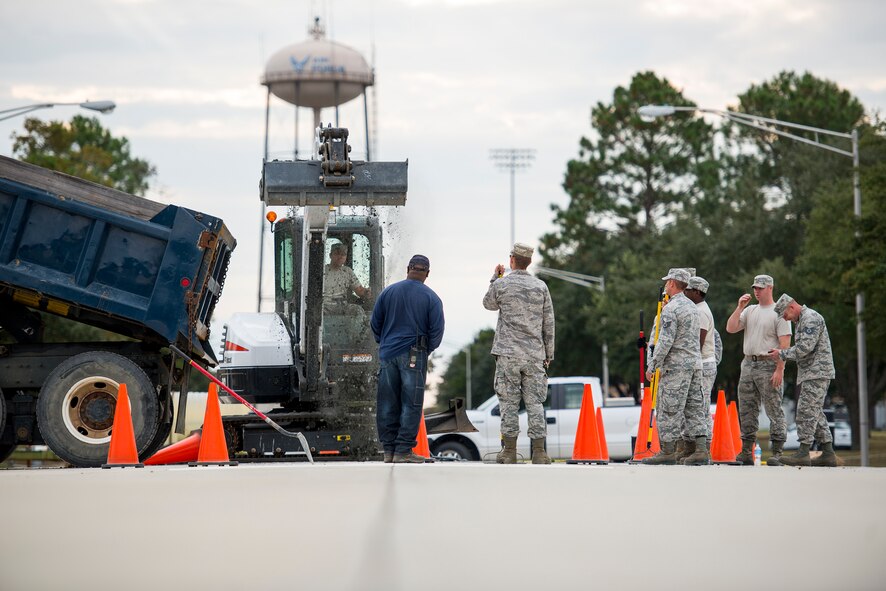 Airmen from the 23d Civil Engineer Squadron pour gravel into a hole Oct. 30, 2014, at Moody Air Force Base, Ga. Prior to pouring the new concrete, the Airmen first had to lay down a foundation to ensure the pavement would settle correctly. (U.S. Air Force photo by Airman 1st Class Ryan Callaghan/Released)