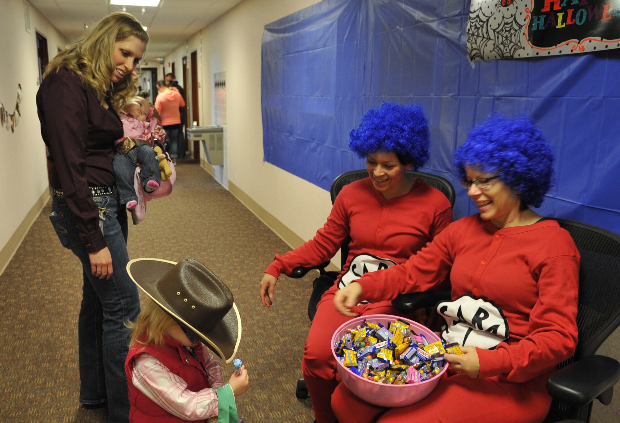 Members of the 319th Medical Group dressed as Thing 1 and Thing 2 from Dr. Seuss’ “The Cat in the Hat,” offer candy to children at the clinic’s annual trick-or-treat event on Grand Forks Air Force Base, N.D. Each office in the clinic created its own theme where children could collect candy, dance to music, and even watch scenes from popular movies. (U.S. Air Force photo/Staff Sgt. Susan L. Davis)