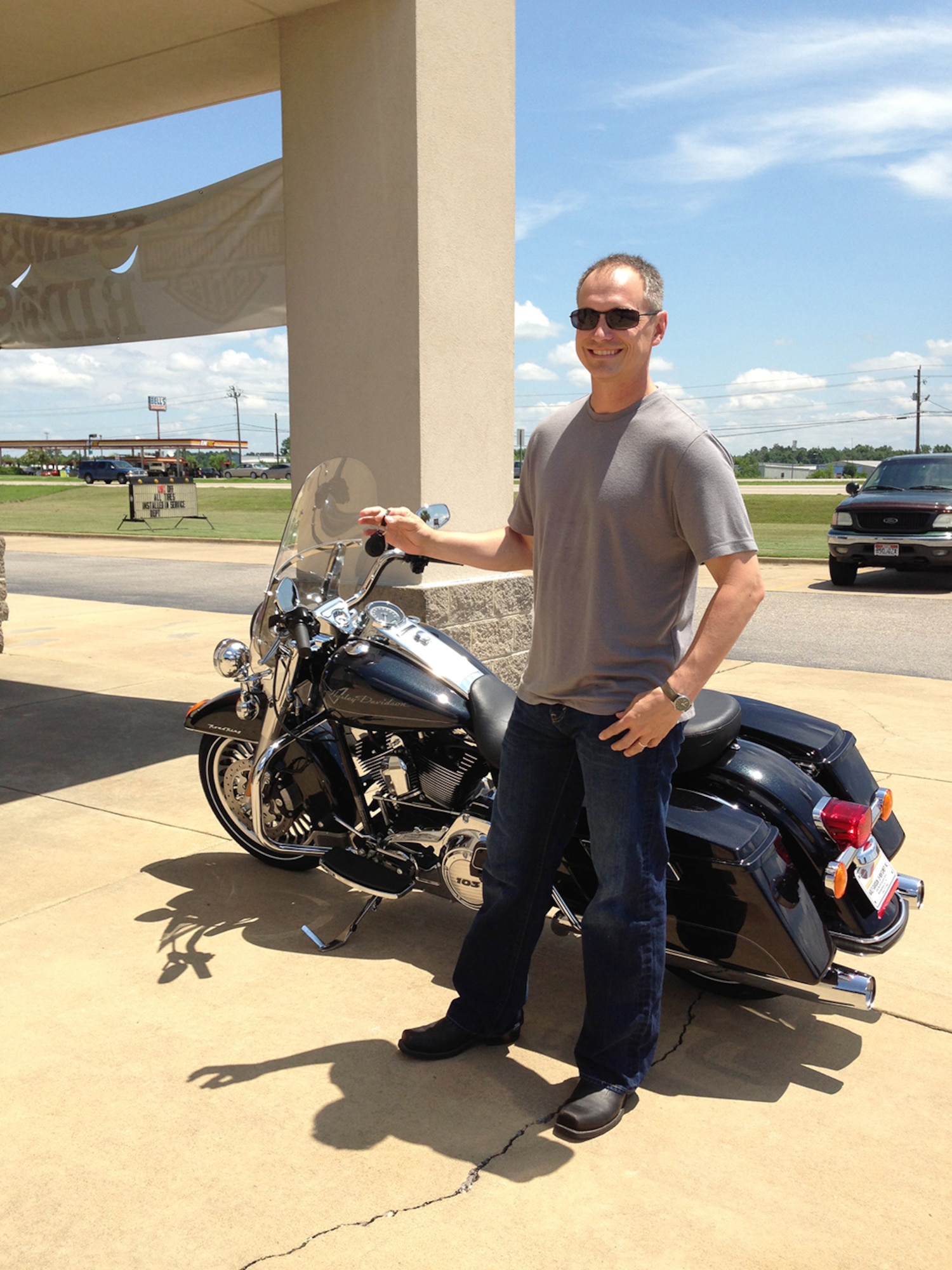 A happy Maj. Jason Ross stands in front of his brand new Harley Davidson Road King in July 2013. Little did he know the motorcycle would be totaled less than a year later while he was attending Air Command and Staff College at Maxwell AFB, Ala. (Courtesy photo by Maj. Jason Ross)