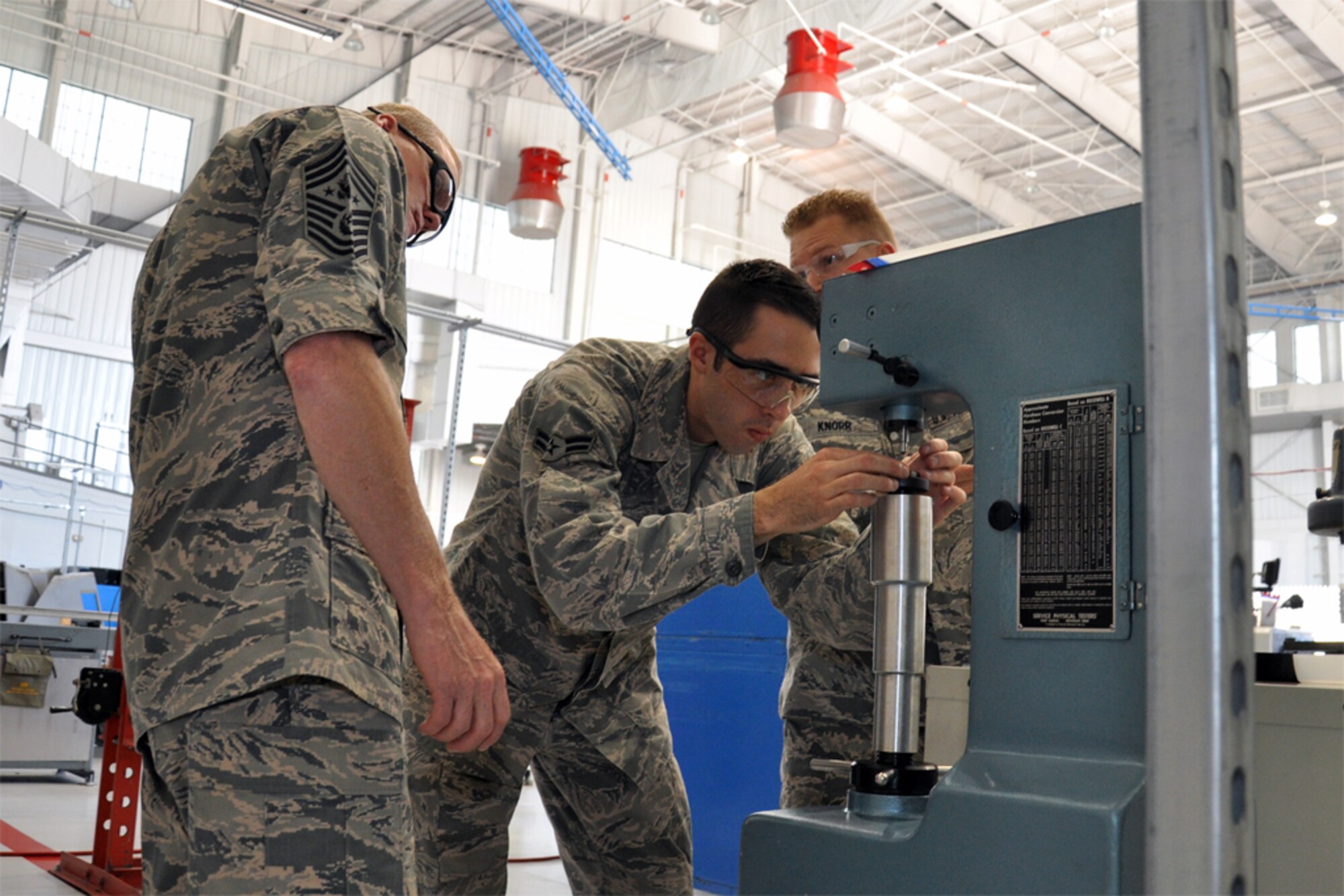 Airman 1st Class Kasey Carter and Staff Sgt. Isaiah Knorr, 916th Air Refueling Wing, demonstrate the use of a metals hardness tester for Chief Master Sgt. of the Air Force James Cody while he visited Seymour Johnson Air Force Base, North Carolina, Oct. 10. During the visit, Cody spent time with Airmen of the 916th ARW and its Total Force Associate partner, the 911th Air Refueling Squadron. (U.S. Air Force photo/Staff Sgt. Alan Abernethy)
