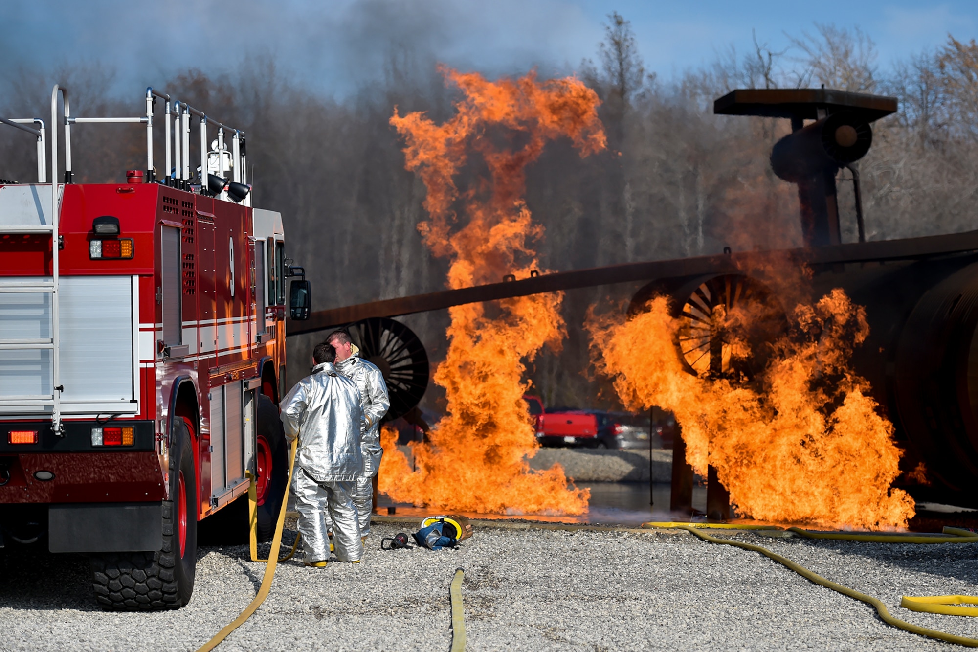 YOUNGSTOWN AIR RESERVE STATION, Ohio -- Firefighters from the 910th Airlift Wing Civil Engineer Fire Department replace fire hose after fighting a controlled fire on a mock aircraft as part of an emergency response capabilities demonstration during the American Red Cross’ Feel the Heat event here, Oct. 27. As the firefighters stow their equipment, excess propane burns off of the mock aircraft frame in the background. An audience of invited guests and area media representatives observed the exercise, which showcased the partnership between the military and the Red Cross as the second event to take place as part of the Air Force Community Partnership Program here, which has been ongoing since June 23, 2014. U.S. Air Force photo by Mr. Eric M. White