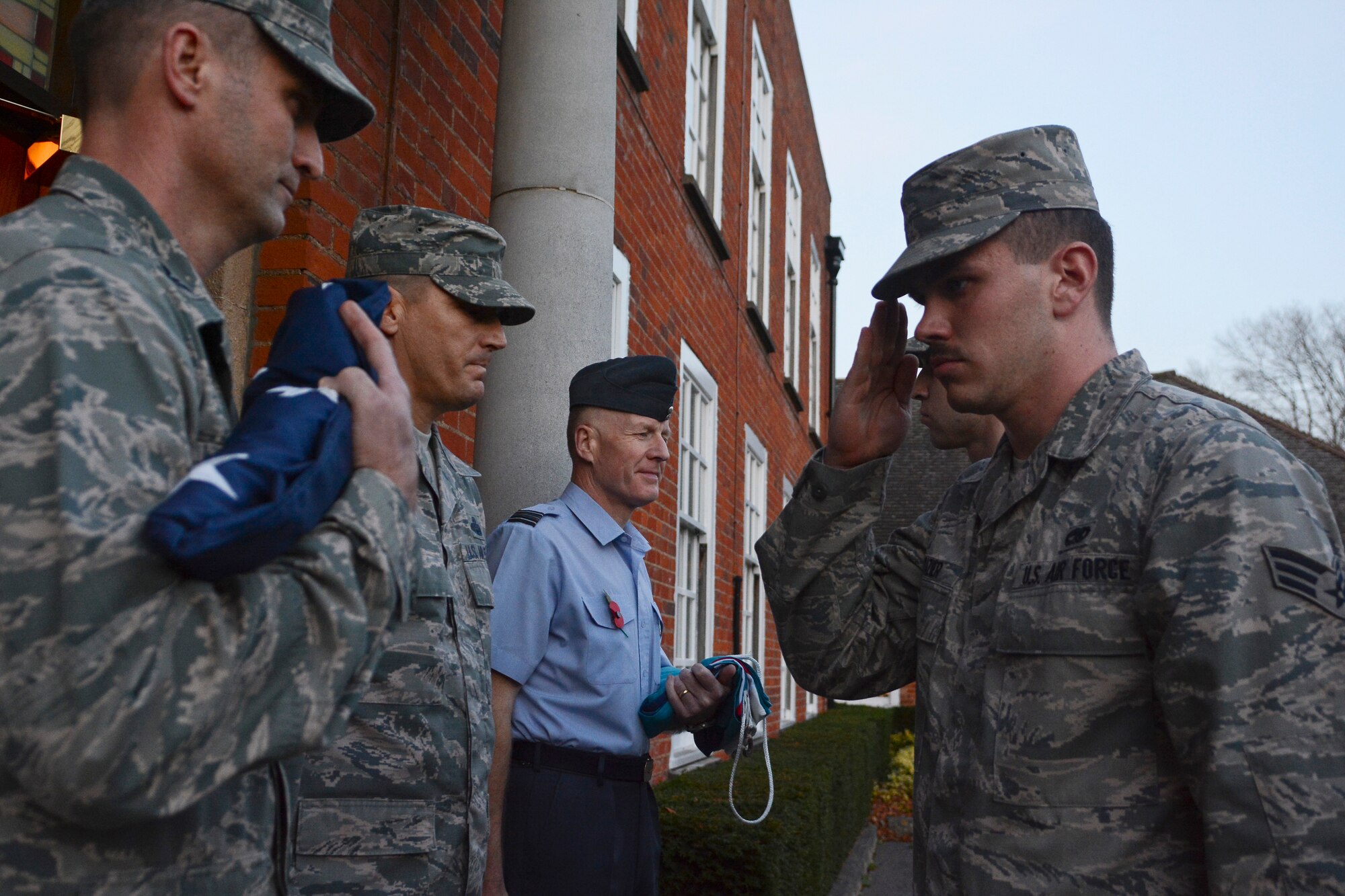 U.S. Air Force Senior Airman Colby Frazier, 100th Maintenance Squadron aircraft fuel systems journeyman from Wichita, Kan., salutes the U.S. flag after presenting it to U.S. Air Force Col. David Cox, left, 100th Air Refueling Wing vice commander during a retreat ceremony Oct. 30, 2014, on RAF Mildenhall England. Retreat is a military tradition that honors the flag and signals the end of the duty day. (U.S. Air Force photo by Staff Sgt. Micaiah Anthony/Released)