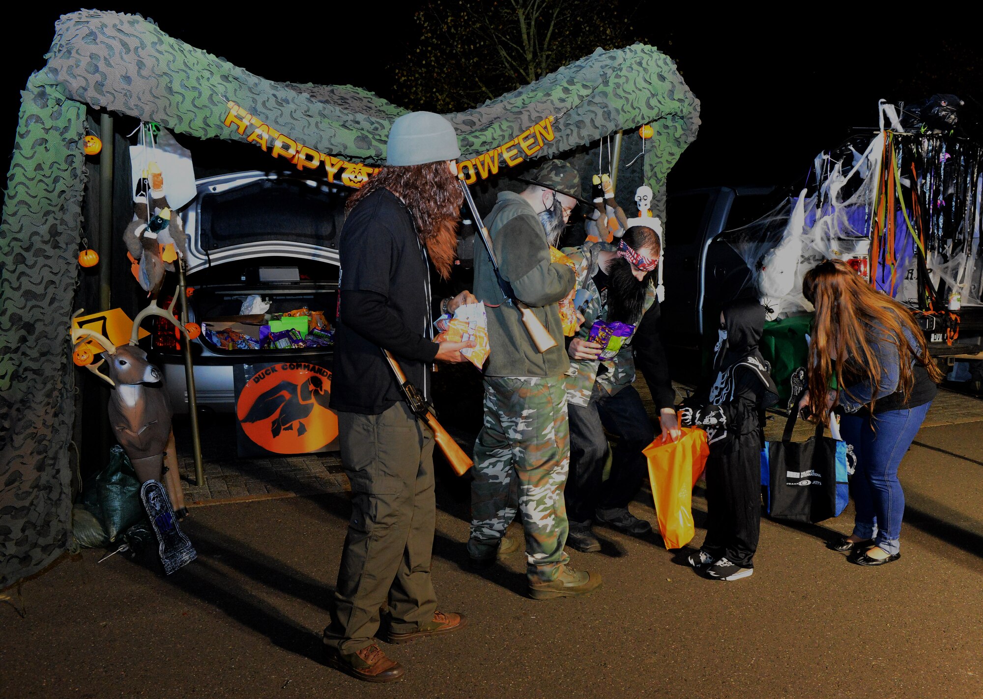 Volunteers for Family Fright Night hand out candy to a trick-or-treater for “Trunk-or-Treat” at the Club Eifel parking lot on Spangdahlem Air Base, Germany, Oct. 30, 2014. “Trunk-or-Treat” allowed trick-or-treaters and their family members to safely get candy from the trunks of decorated vehicles. (U.S. Air Force photo by Airman 1st Class Luke Kitterman/Released)