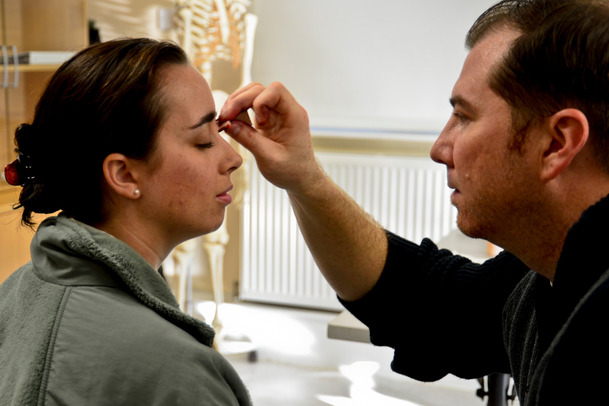 Dave Scott, 48th Medical Group contractor, applies make-up to Senior Airman Ashley E. Pike, 48th Medical Support Squadron medical logistics technician, to simulate a black eye at Royal Air Force Lakenheath, England, Oct. 28, 2014. Several Airmen volunteered to wear make-up simulating black-eyes to raise awareness about domestic violence. (U.S. Air Force Photo by Airman 1st Class Erin R. Babis/Released)