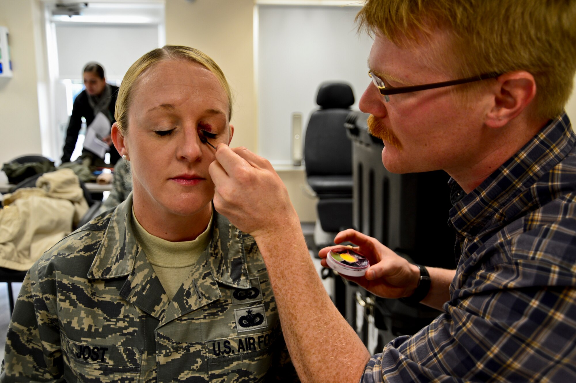 Jeremy Kossbiel, 48th Medical Group contractor, applies make-up to Master Sgt. Angelique Jost, 48th Fighter Wing inspector general, to simulate a black eye at Royal Air Force Lakenheath, England, Oct. 28, 2014. October is Domestic Violence Awareness month and the black-eye campaign was planned to reach out and educate Airmen on the issue and how to report it. (U.S. Air Force Photo by Airman 1st Class Erin R. Babis/Released)