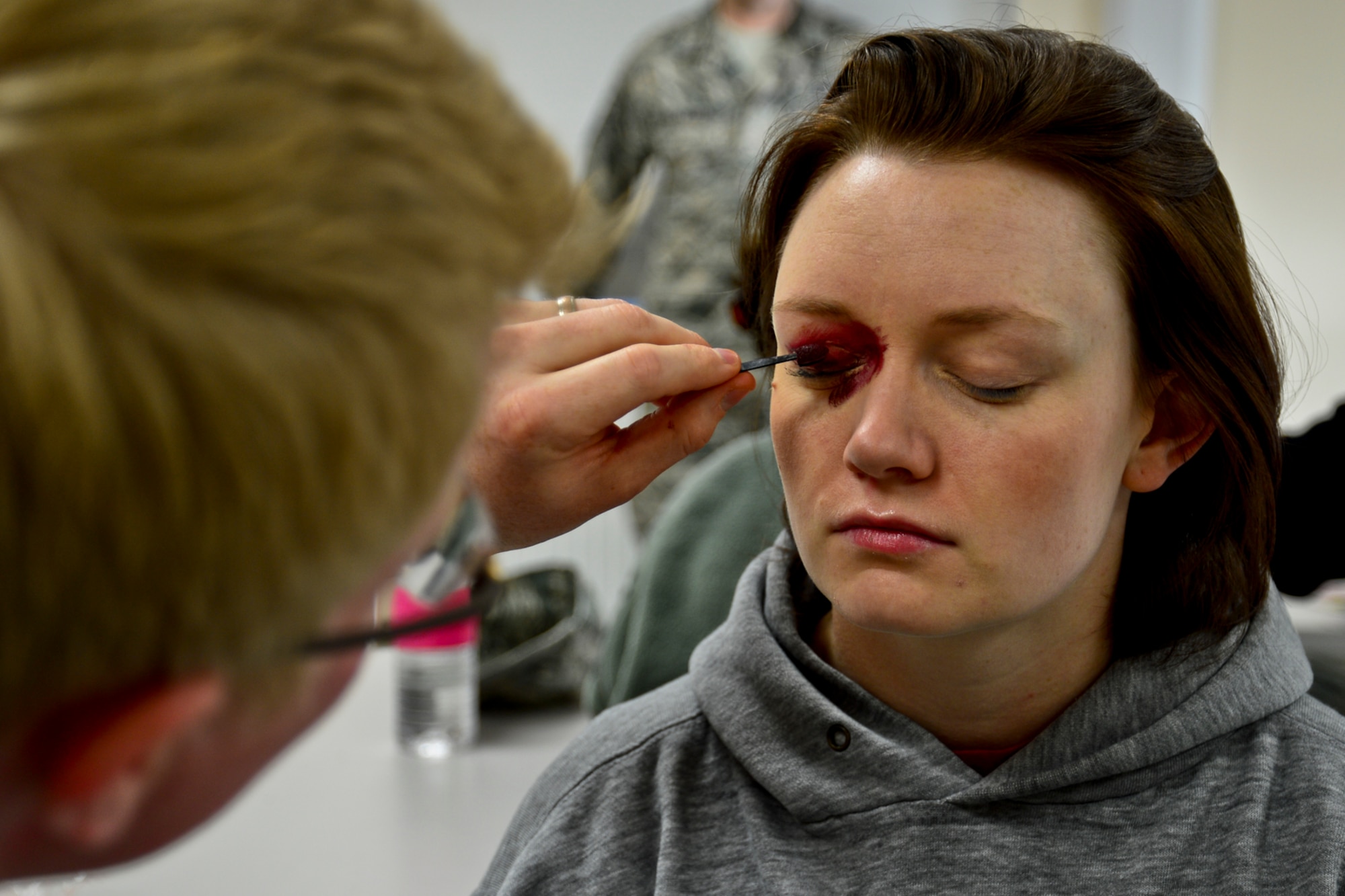 Jeremy Kossbiel, 48th Medical Group contractor, applies make-up to Senior Airman Larissa Hayes, 48th Equipment Maintenance Squadron phase avionics journeyman, to simulate a black eye at Royal Air Force Lakenheath, England, Oct. 28, 2014. Several Airmen volunteered to wear make-up simulating black-eyes to raise awareness about domestic violence. (U.S. Air Force Photo by Airman 1st Class Erin R. Babis/Released)