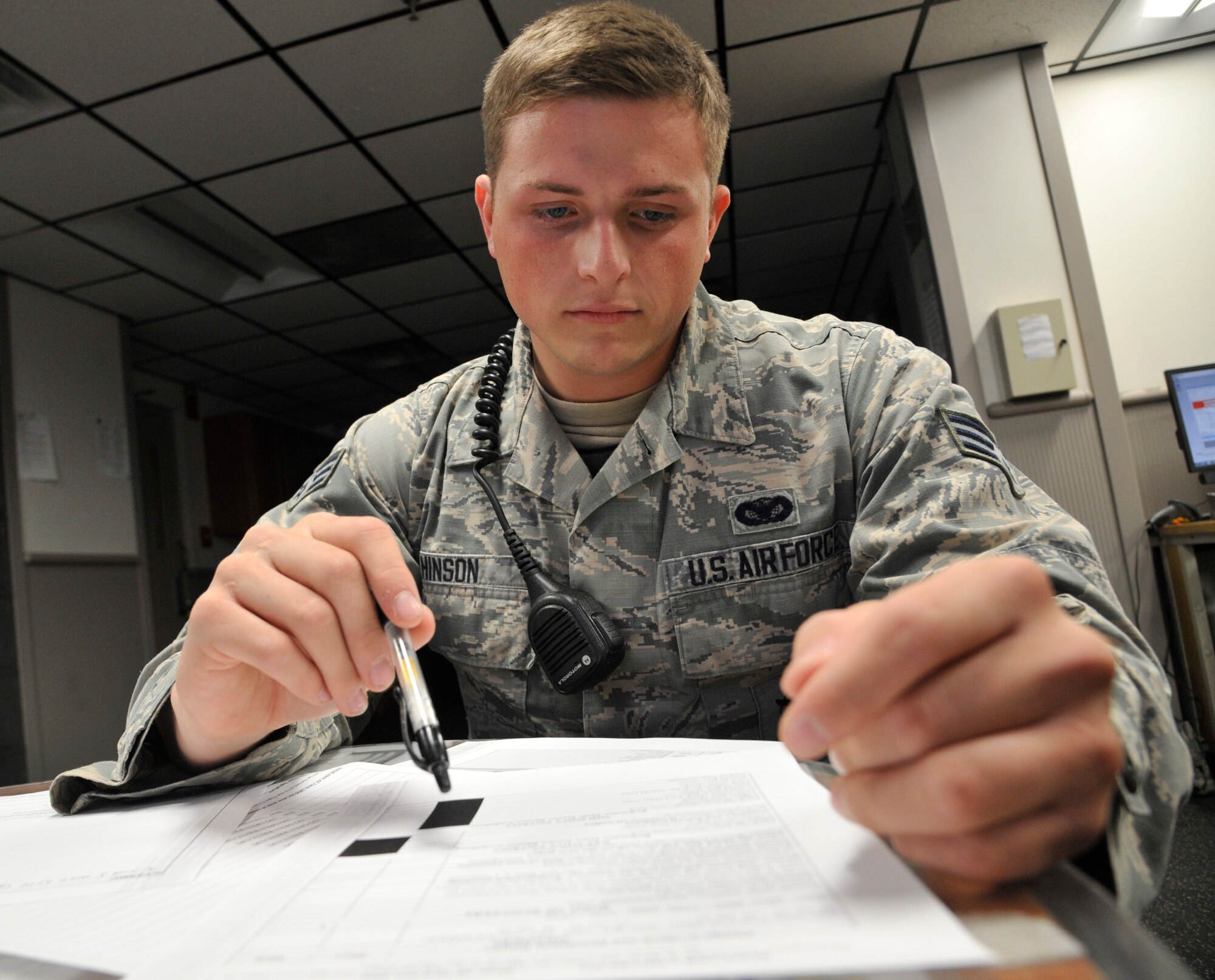 U.S. Air Force Senior Airman Matthew Hinson, 509th Security Forces Squadron patrolman, reviews daily paperwork at Whiteman Air Force Base, Mo., Oct. 8, 2014. Whenever a situation occurs around the base, the desk Sgt. will alert patrolmen and dispatch to the location where situation is occurring. (U.S. Air Force photo by Airman 1st Class Keenan Berry/Released)