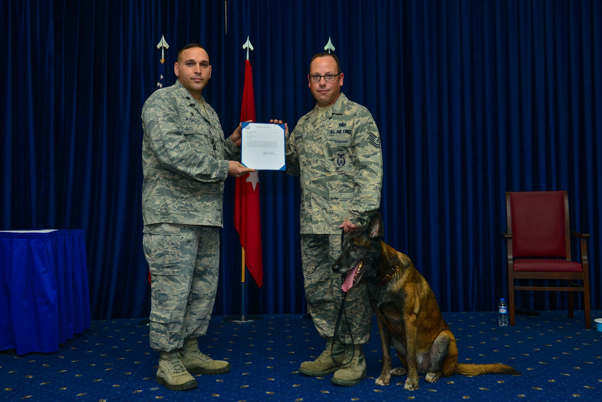 Lt. Col. Joseph Musacchia, 39th Security Forces Squadron commander, hands a certificate of retirement to Tech. Sgt. Kenneth Fresquez, 39th SFS kennel master, for Kira, 39th SFS military working dog Oct. 27, 2014, Incirlik Air Base, Turkey.  Staff Sgt. Alexandra Woodlee, 39th SFS MWD handler, will be making the transition to civilian life with Kira after her adoption. (U.S. Air Force photo by Senior Airman Nicole Sikorski/Released)
