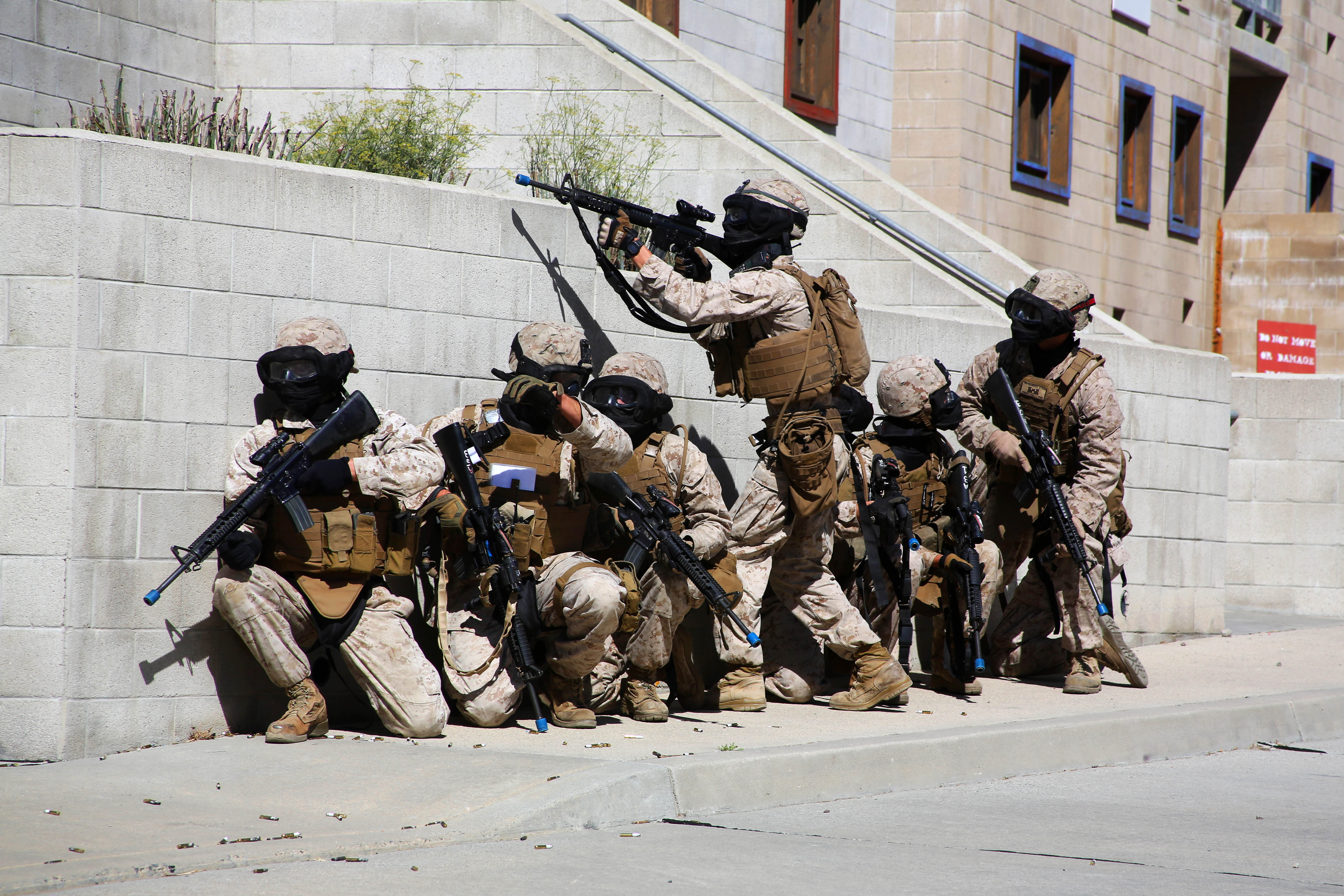 Marines take cover behind a wall during a training evolution using