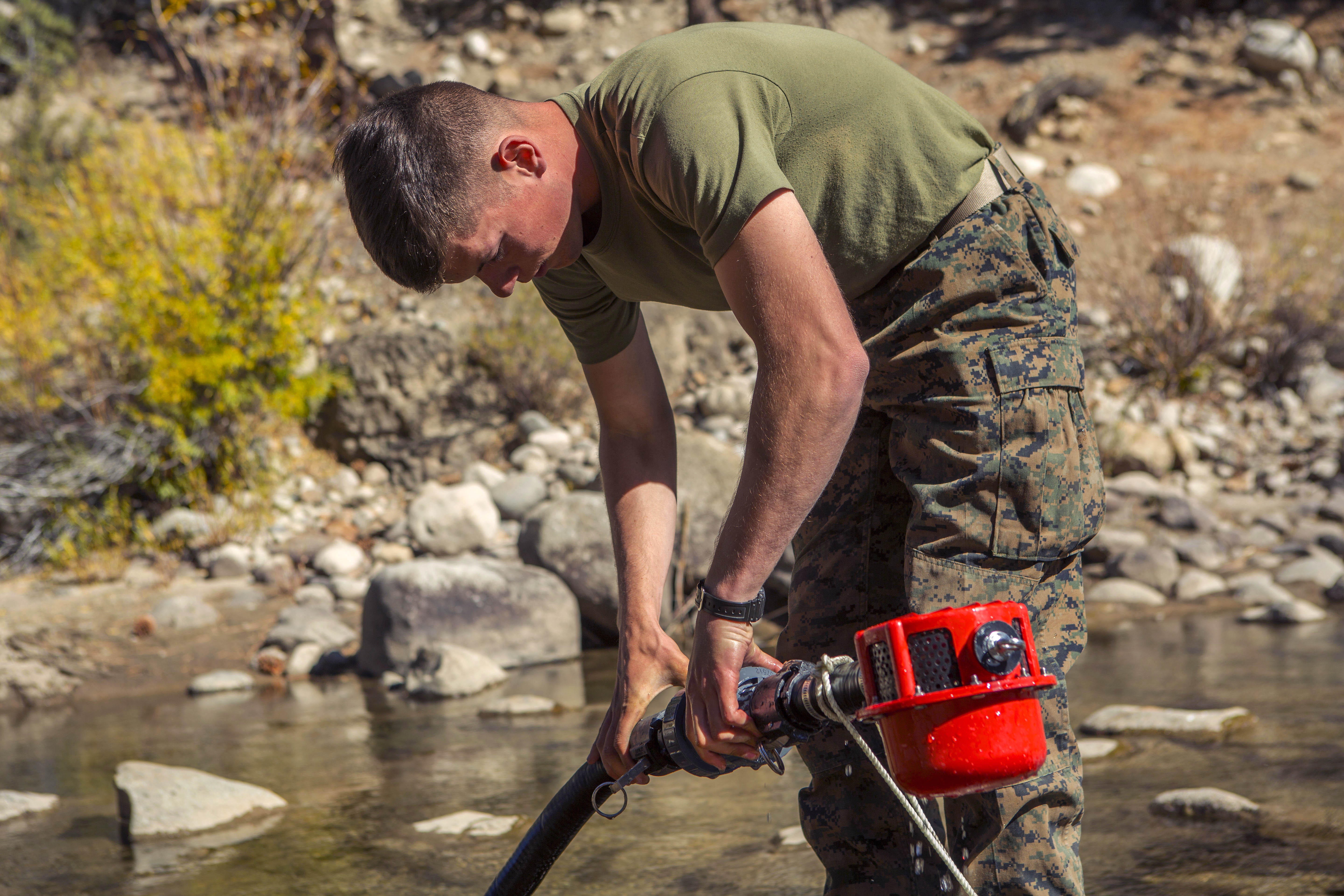 Marine Corps Lance Cpl. Michael R. Holmes purifies river water using a
