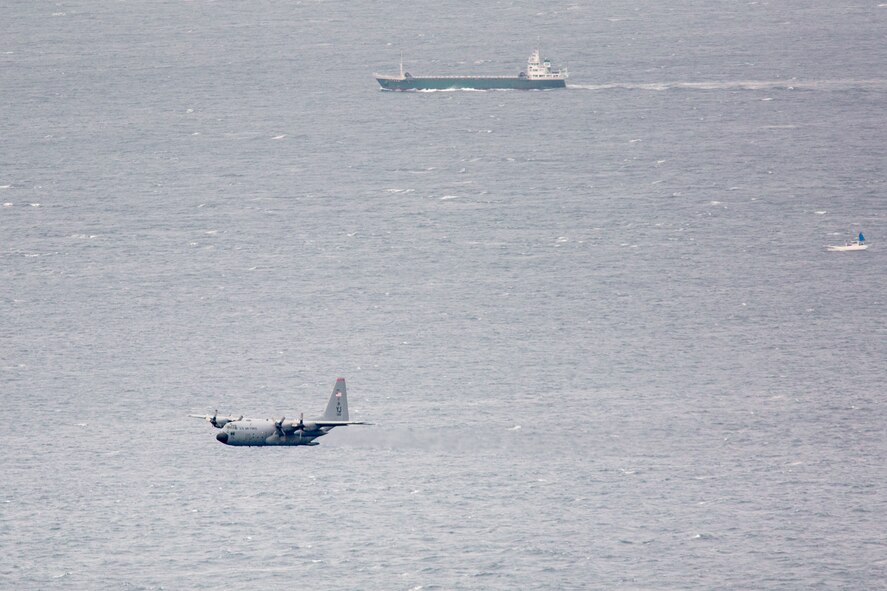 A C-130 Hercules from the 36th Airlift Squadron flies over Sagami bay, Shizuoka prefecture, Japan, Aug. 31, 2014, during the Shizuoka Comprehensive Disaster Drill.  Crewmembers from the 36th AS engaged a water low-cost, low-altitude (LCLA) airdrop for the first time in the waters near Honshu Island. (U.S. Air Force photo by Osakabe Yasuo/Released)