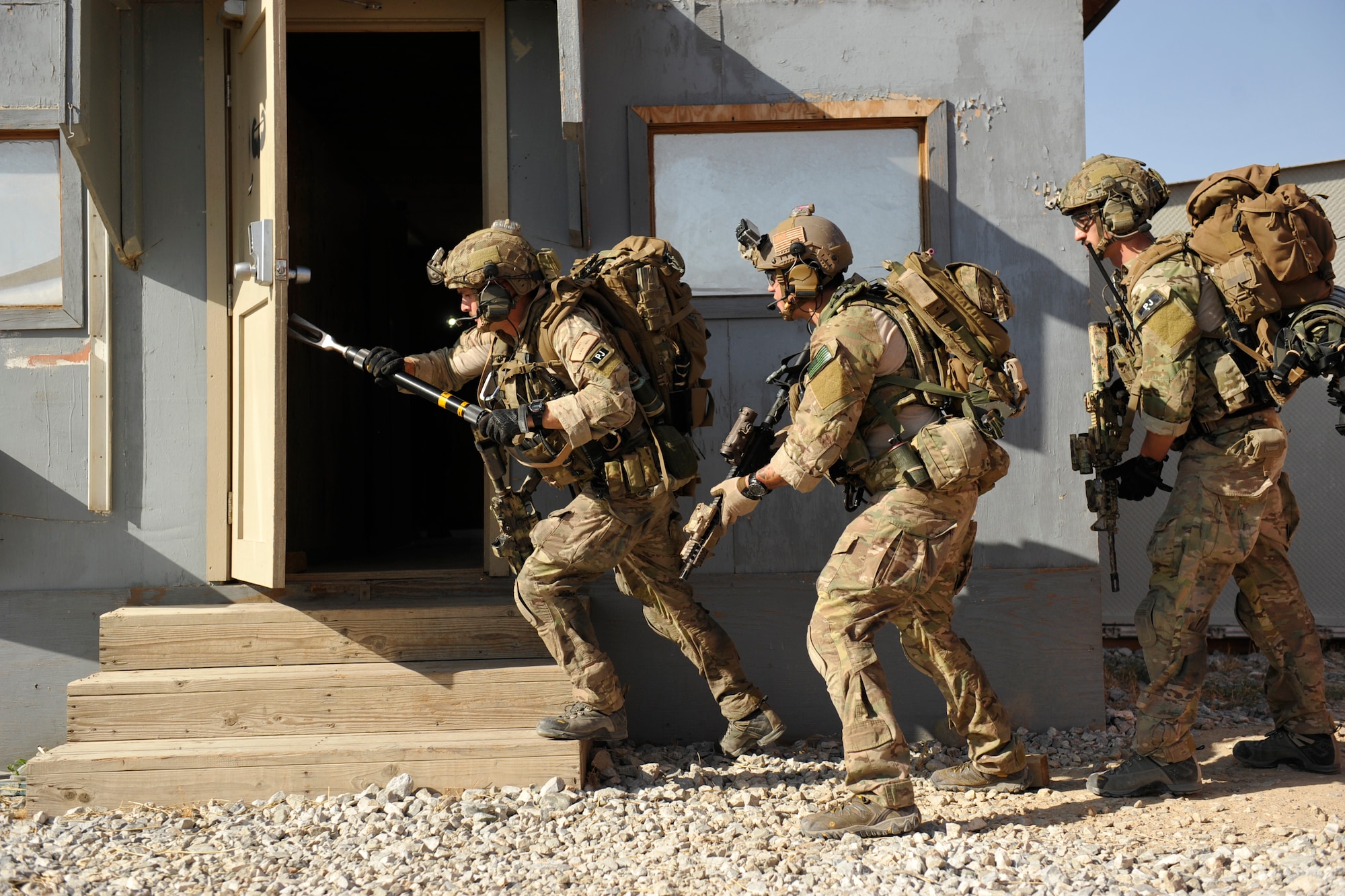 Airmen assigned to the 83rd Expeditionary Rescue Squadron  breach a door and prepare to clear a room during a mission rehearsal in an excess structure here Aug. 26, 2014. The event allowed pararescuemen from the 83rd Expeditionary Rescue Squadron to hone their breaching, clearing, patient care and egress skills. Air Force rescue forces conduct combat search and rescue and personnel recovery operations. Brady and Schalin are deployed from Davis-Monthan Air Force Base, Ariz., and Lee is an Air National Guardsmen deployed from the 123rd Special Tactics Squadron, Louisville, Ky. The 83rd ERQS partnered with Joint Task Force Trailblazer, U.S. Army 2nd Engineer Brigade, to use the structure prior to its scheduled deconstruction. Task Force Trailblazer is currently demolishing 50-70 wooden structures here each week as part of Operation Enduring Freedom retrograde operations. (U.S. Air Force photo by Maj. Brandon Lingle/Released)