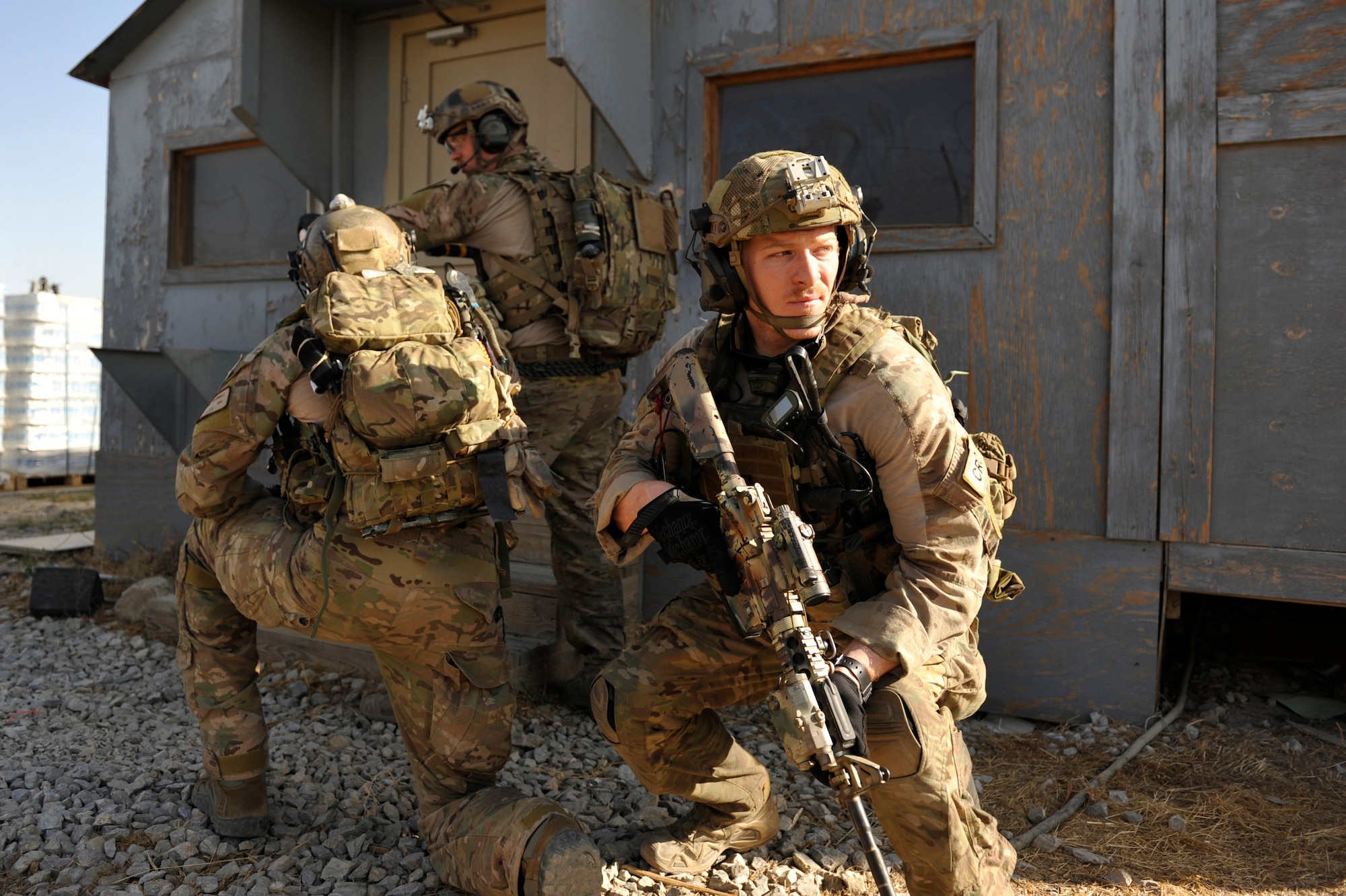 An 83rd Expeditionary Rescue Squadron combat rescue officer, watches for potential threats as his teammates breach a door during a mission rehearsal in an excess structure here Aug. 26, 2014. The event allowed PJs to hone their breaching, clearing, patient care and egress skills. Air Force rescue forces conduct combat search and rescue and personnel recovery operations. Rochelle is deployed from Davis-Monthan Air Force Base, Ariz. The 83rd ERQS partnered with Joint Task Force Trailblazer, U.S. Army 2nd Engineer Brigade, to use the structure prior to its scheduled deconstruction. Task Force Trailblazer is currently demolishing 50-70 wooden structures here each week as part of Operation Enduring Freedom retrograde operations. (U.S. Air Force photo by Maj. Brandon Lingle/Released)