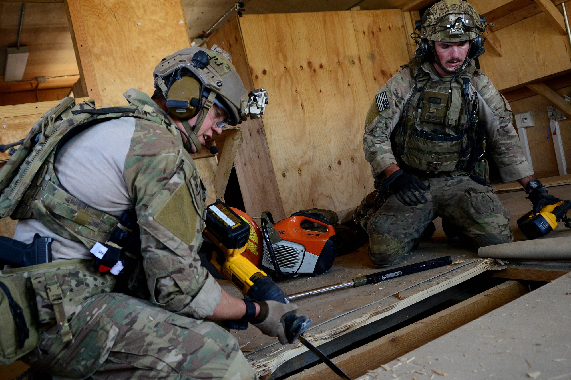 Airmen assigned to the 83rd Expeditionary Rescue Squadron tear boards from a building’s floor at Bagram Airfield, Afghanistan Aug. 26, 2014.  During the mission rehearsal, they breached and cleared a building to rescue a simulated casualty. U.S. Air Force photo by Staff Sgt. Evelyn Chavez/Released)