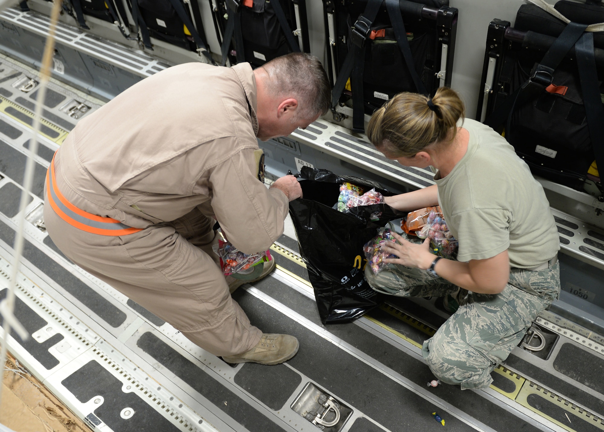 Master Sgts. Stephen Brown (left) and Emily Edmunds, 816th Expeditionary Airlift Squadron loadmasters, sort candy to attach to container delivery system bundles filled with fresh drinking water on a C-17 Globemaster III in preparation for a humanitarian airdrop  Aug. 30, 2014, over the area if Amirli, Iraq. The candy was collected by the squadron to supplement United States government humanitarian aid. (U.S. Air Force photo/Staff Sgt. Shawn Nickel)