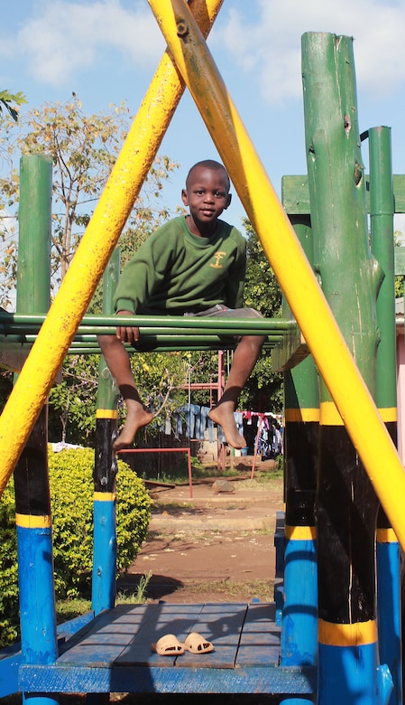 A young resident of Samaritan Village orphanage near Arusha, Tanzania, poses atop new playground equipment constructed in August 2014 by a volunteer team from Yuba City, California.