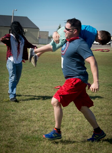 A runner carries a child away from a zombie at Minot Air Force Base, N.D., Aug. 30, 2014. The runners’ goal was to make it across the field without having their flag captured by a zombie. (U.S. Air Force photo/Airman 1st Class Sahara L. Fales)