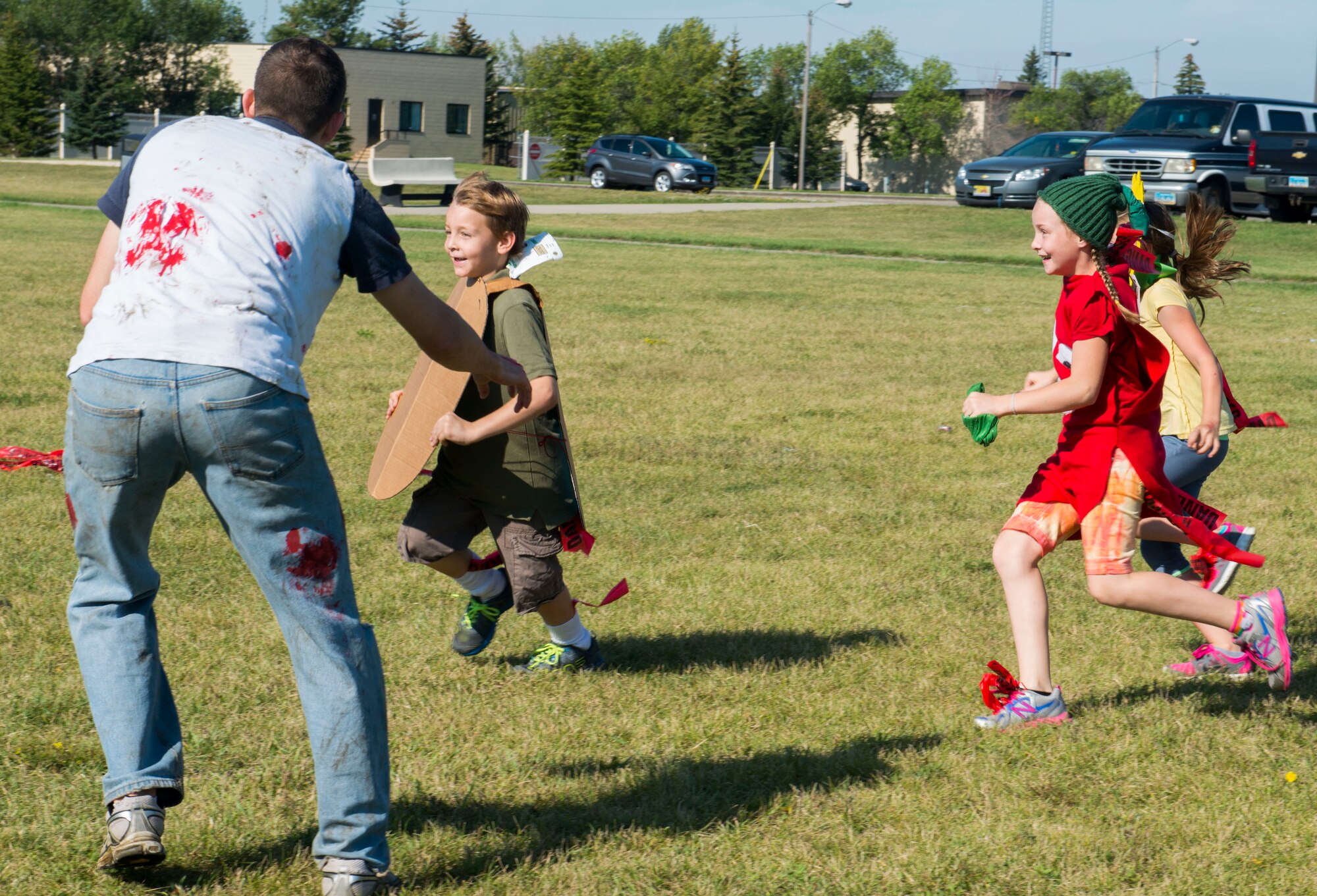 A zombie chases children at Minot Air Force Base, N.D., Aug. 30, 2014. The Apocalypse Runs North 5K allowed Airmen and their families to participate as either zombies or runners. (U.S. Air Force photo/Airman 1st Class Sahara L. Fales)