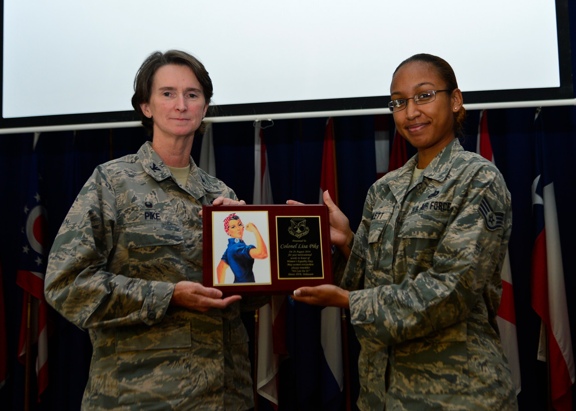 Col. Lisa Pike, 436th Mission Support Group commander, holds a plaque presented to her by Staff Sgt. Luzviminda Hamlett, 436th Force Support Squadron career development supervisor, during the Women’s Equality Day luncheon Aug. 26, 2014, at the Landings on Dover Air Force Base, Del. Pike was the guest speaker at the event and was presented with the plaque for her motivational work in honor of Women’s Equality Day. (U.S. Air Force photo/Airman 1st Class William Johnson)