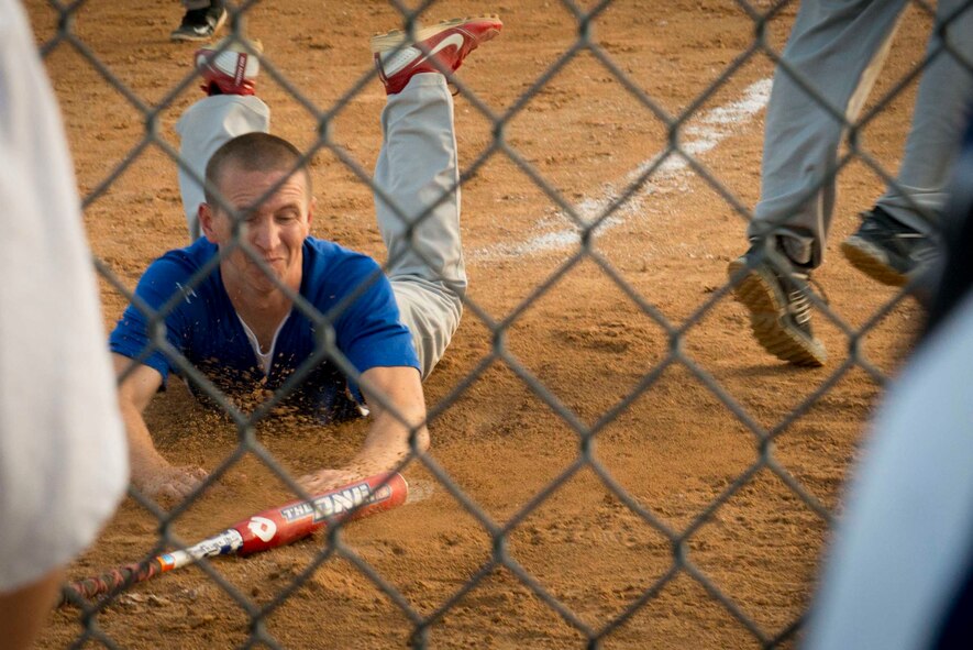Michael Phillips, captain of the 705th Munitions Squadron softball team, dives onto home plate at Minot Air Force Base, N.D., Aug. 26, 2014. This was the final play of the intramural softball game that gave the MUNS team the championship title. (U.S. Air Force photo/Airman 1st Class Sahara L. Fales)