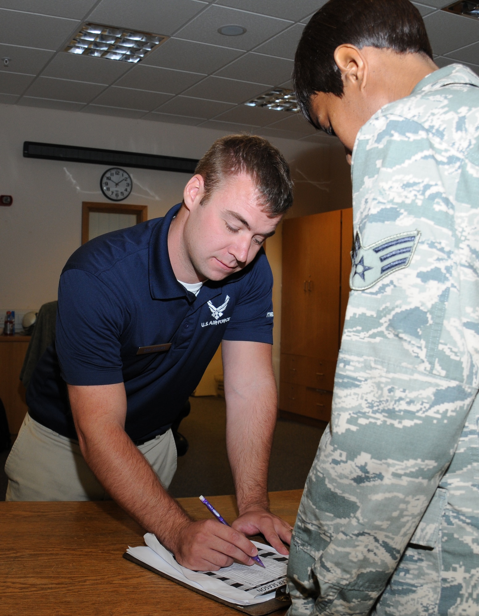 U.S. Air Force Senior Airman Corey Adams, left, 100th Force Support Squadron Sports director of the Hardstand Fitness Center from New Lothrop, Mich., assists a customer with paperwork Aug. 20, 2014, on RAF Mildenhall, England. Adams and his team work shifts to assist customers throughout the day. (U.S. Air Force photo/Gina Randall/Released)