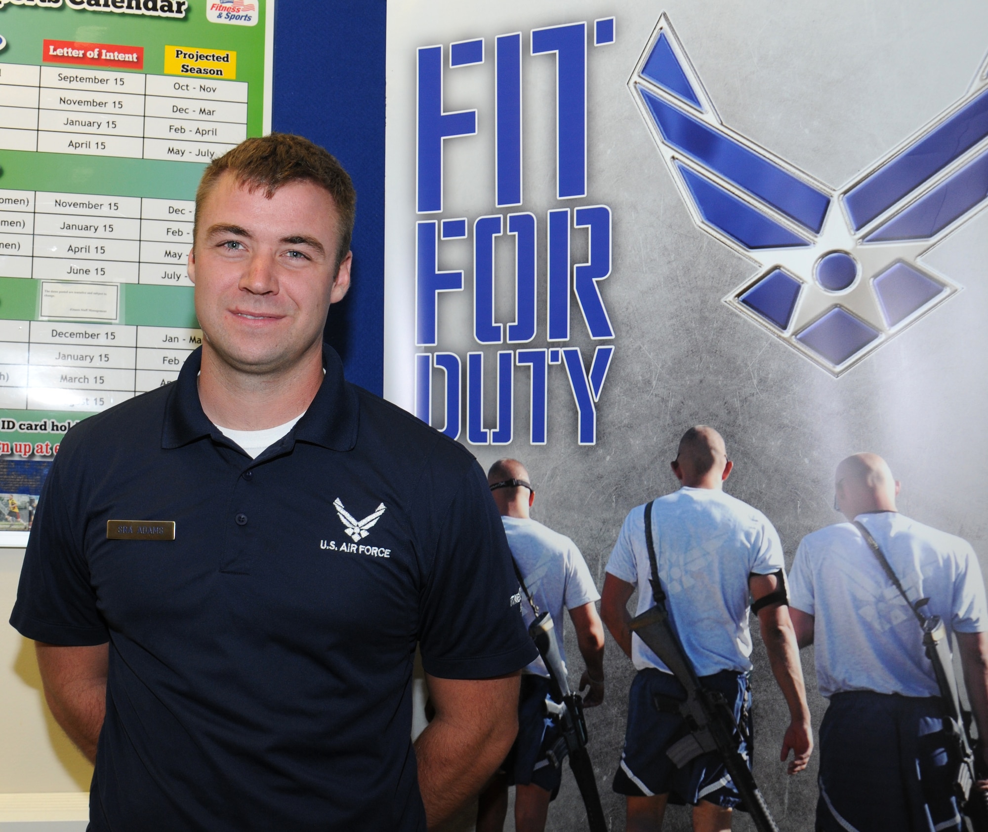 U.S. Air Force Senior Airman Corey Adams, 100th Force Support Squadron Sports director of the Hardstand Fitness Center from New Lothrop, Mich., poses for a photograph in front of a motivational poster Aug. 20, 2014, on RAF Mildenhall, England. Adams’ role is varied and includes answering questions, field preparation for various sports and organizing official contracts. (U.S. Air Force photo/Gina Randall/Released)