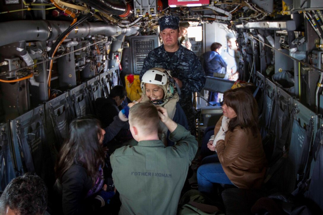 Children from a local school try on the flight gear worn by MV-22 crew members on an MV-22 Osprey during a tour aboard the future amphibious assault ship USS America (LHA 6) in Valparaiso, Chile, Aug. 25, 2014. The children were given the opportunity to get hands on with several static displays hosted by Marines and Sailors showcasing the capabilities that Special Purpose Marine Air Ground Task Force South brings to the ship. SPMAGTF-South is embarked aboard America in support of her maiden transit “America Visits the Americas.” The transit demonstrates the capabilities that the Navy-Marine Corps team brings to our nation and partners. (U.S. Marine Corps photo by Cpl. Donald Holbert/Released)