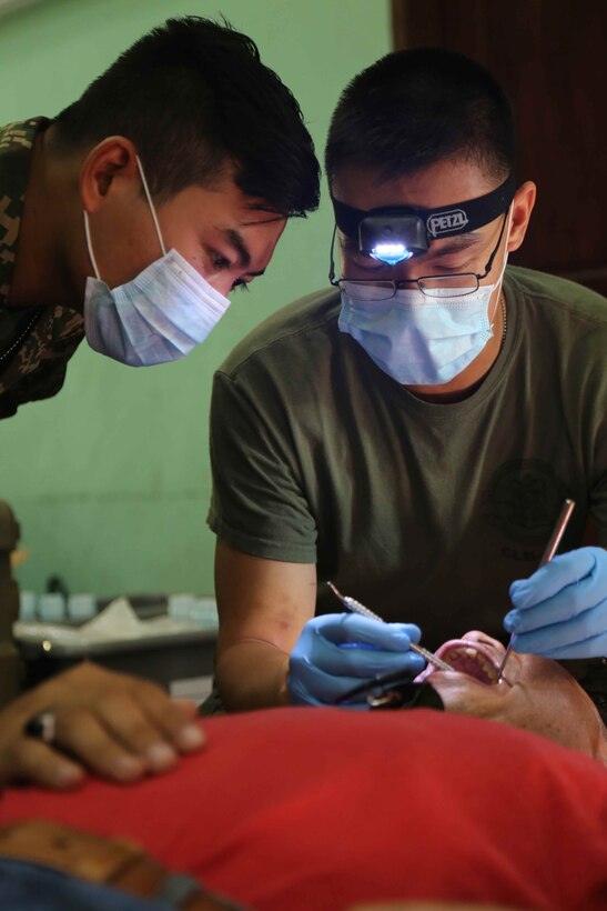 Lt. Anthony Chia, a dentist with Combat Logistics Battalion 11, 11th Marine Expeditionary Unit, and a Malaysian dentist examine a Malaysian patient during a medical and dental outreach partnered with the Royal Malaysian Medical Corps as part of Malaysia-United States Amphibious Exercise 2014. During the first day of the outreach, doctors and dentists treated 159 medical and 70 dental patients. During MALUS AMPHEX 14, Marines with the 11th MEU conduct partnered training with the Malaysian Armed Forces including shipboard familiarization, medical and dental training, and weapons familiarization.  (U.S. Marine Corps photo by Gunnery Sgt. Rome M. Lazarus/Released)