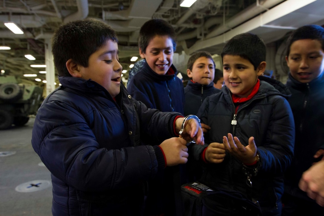 Children from a local school explore the law enforcement equipment at a non-lethal weapons static display aboard the future amphibious assault ship USS America (LHA 6) in Valparaiso, Chile, Aug. 25, 2014. The children were given the opportunity to get hands on with several static displays hosted by Marines and Sailors showcasing the capabilities that Special Purpose Marine Air Ground Task Force-South brings to the Ship. SPMAGTF-South is embarked aboard America in support of her maiden transit “America Visits the Americas.” The transit demonstrates the capabilities that the Navy-Marine Corps team brings to our nation and partners. (U.S. Marine Corps photo by Cpl. Donald Holbert/ Released)