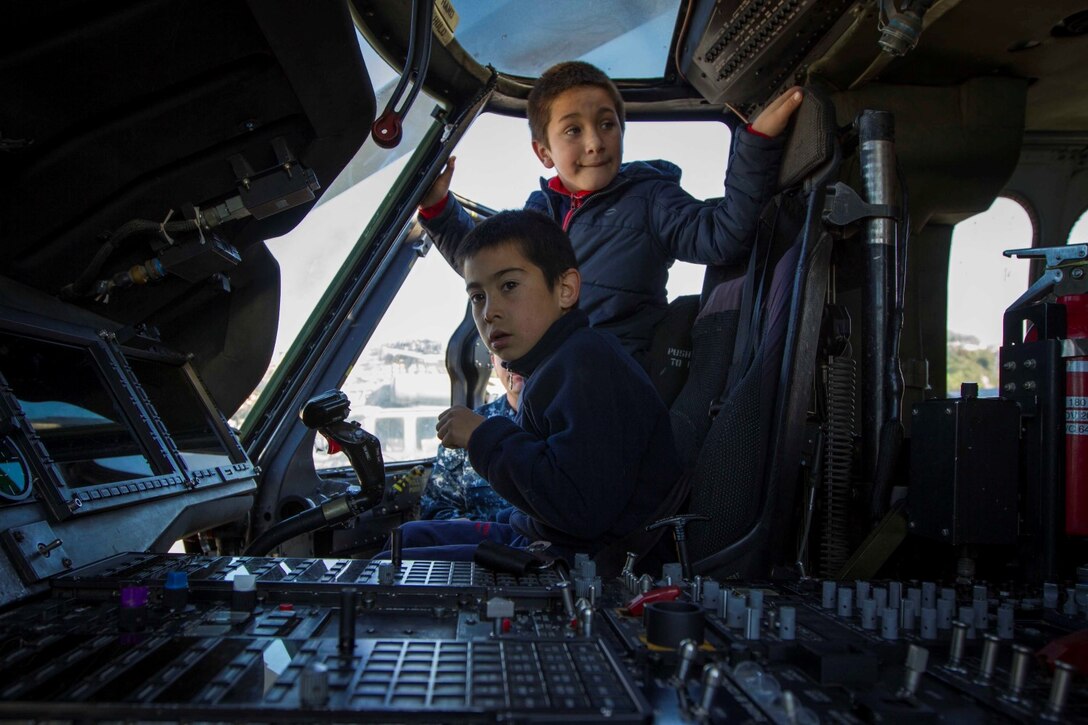 Students from a local school sit in the cockpit of an MH-60S Seahawk during a tour of the future amphibious assault ship USS America (LHA 6) in Valparaiso, Chile, Aug. 25, 2014. The children were given the opportunity to get hands on with several static displays hosted by Marines and Sailors showcasing the capabilities that Special Purpose Marine Air Ground Task Force South brings to the ship. SPMAGTF-South is embarked aboard America in support of her maiden transit “America Visits the Americas.” The transit demonstrates the capabilities that the Navy-Marine Corps team brings to our nation and partners. (U.S. Marine Corps photo by Cpl. Donald Holbert/ Released)