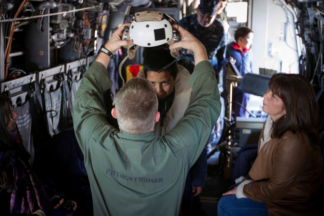 Children from a local school try on the flight gear worn by MV-22 crew members on an MV-22 Osprey during a tour aboard the future amphibious assault ship USS America (LHA 6) in Valparaiso, Chile, Aug. 25, 2014. The children were given the opportunity to get hands on with several static displays hosted by Marines and Sailors showcasing the capabilities that Special Purpose Marine Air Ground Task Force South brings to the ship. SPMAGTF-South is embarked aboard America in support of her maiden transit “America Visits the Americas.” The transit demonstrates the capabilities that the Navy-Marine Corps team brings to our nation and partners. (U.S. Marine Corps photo by Cpl. Donald Holbert/Released)