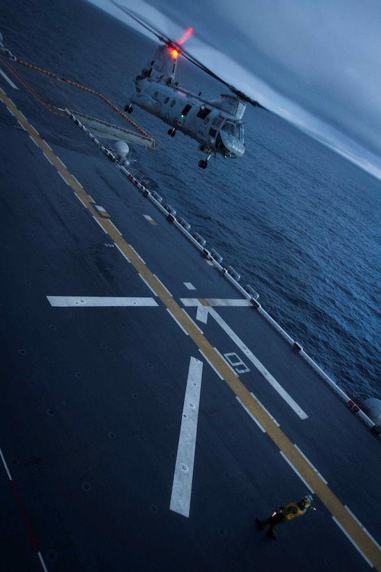 An aircraft handler with the future amphibious assault ship USS America (LHA 6) signals to the pilot of a CH-46E Sea Knight helicopter with Marine Medium Helicopter Squadron 364 to land on the flight deck of the ship, Aug. 24, 2014. Four helicopters with the squadron arrived aboard America ending the exercise Partnership of the Americas 2014. POA was based on a simulated humanitarian assistance and disaster relief scenario in Chile. Multiple nations came together to plan and execute a multi-lateral exercise in response to the HA/DR scenario. Exercises like POA allow the U.S. and our partners in the region to respond to and address transnational and global challenges. America is currently transiting through the U.S. Southern Command’s area of responsibility on her maiden transit “America Visits the Americas.” (U.S. Marine Corps Photo by Cpl. Donald Holbert/ Released)