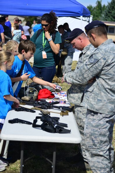 Airmen assigned to the 341st Security Forces Group show off several weapons they use during daily operations at the base track during the annual picnic Aug 28. More than 4,100 Airmen, DoD civilians, retirees and family members showed up at the park to enjoy some sun, food and fun during the base picnic. (U.S. Air Force photo/Tech. Sgt. Chad Thompson)