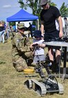 Staff Sgt. Tanner Tilton, 341st Civil Engineer Squadron explosive ordnance disposal technician, shows onlookers how to operate one of the unit's robots near the base track Aug. 28. More than 4,100 Airmen, DoD civilians, retirees and family members showed up at Sun Plaza Park to enjoy some sun, food and fun during the base picnic. (U.S. Air Force photo/Tech. Sgt. Chad Thompson)