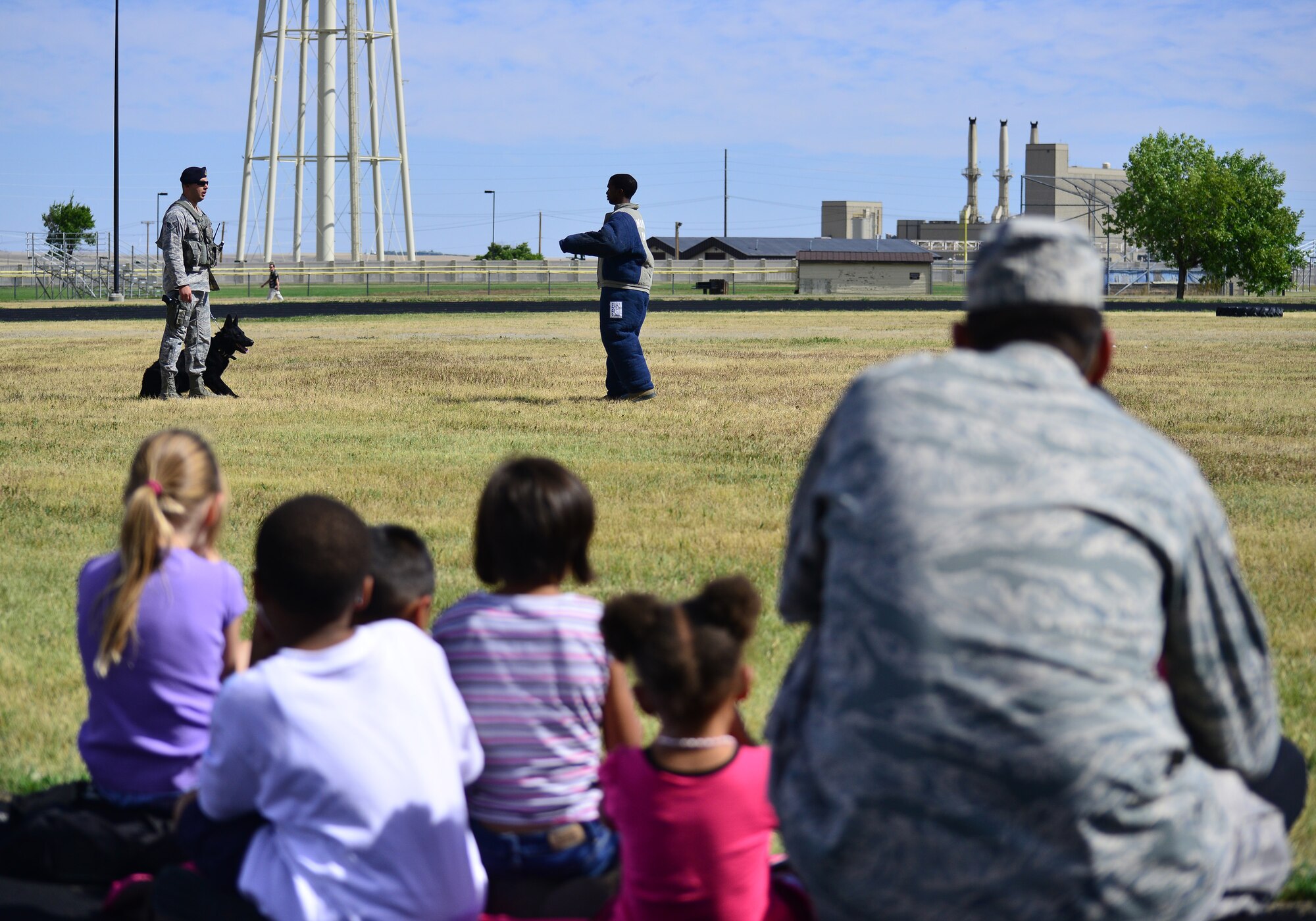 Onlookers watch a military working dog demonstration hosted by the 341st Security Forces Squadron military working dog handlers near the base track Aug. 28. More than 4,100 Airmen, DoD civilians, retirees and family members showed up at Sun Plaza Park to enjoy some sun, food and fun during the base picnic. (U.S. Air Force photo/Tech. Sgt. Chad Thompson)
