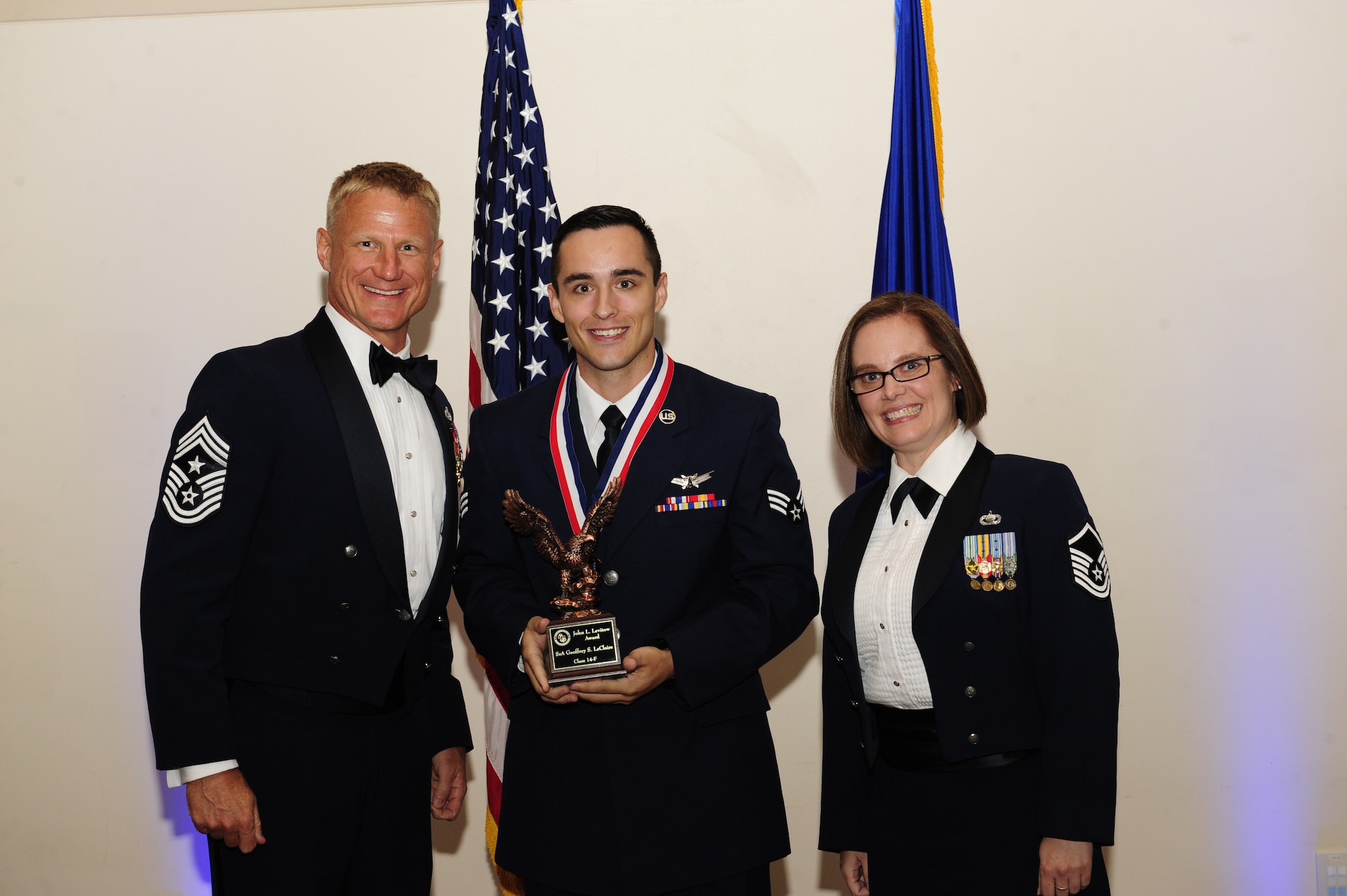 Senior Airman Geoffrey LeClaire, 2nd Space Warning Squadron space system operator, center, receives the John L. Levitow Award during the Buckley Airman Leadership School Class 14-F graduation Aug. 28, 2014, at the Leadership Development Center on Buckley Air Force Base, Colo. The Levitow Award is given to the ALS graduate with the highest academic scores and leadership potential. (U.S. Air Force photo by Airman 1st Class Samantha Saulsbury/Released)