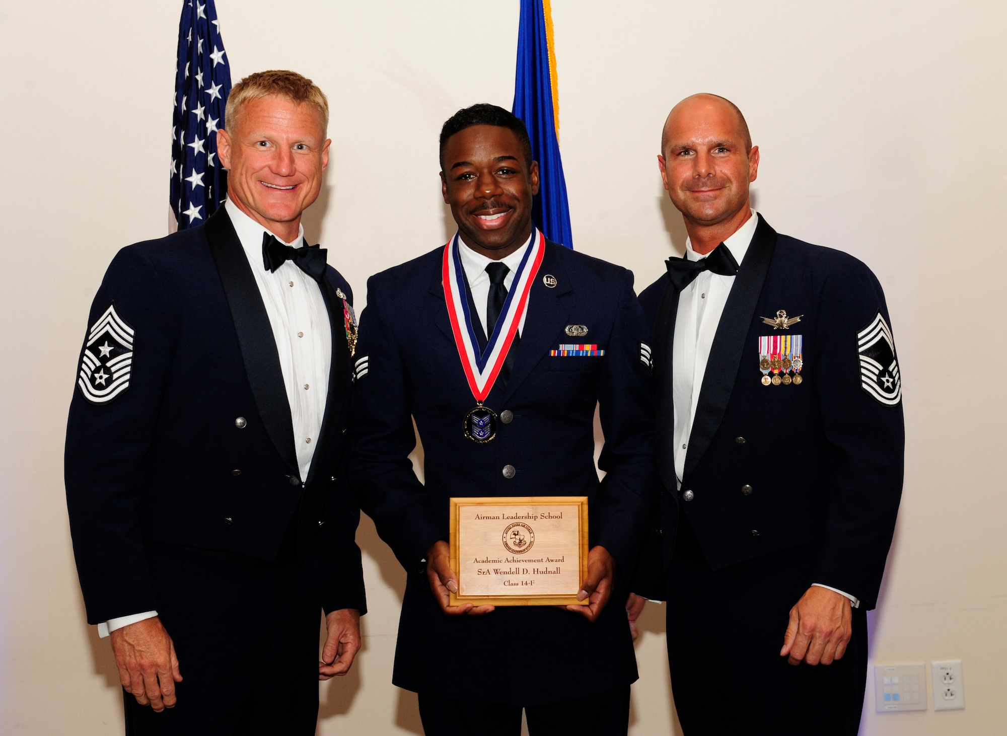 Senior Airman Wendell Hudnall, 460th Space Communications Squadron defense red switch network technician, center, receives the Academic Achievement Award during the Buckley Airman Leadership School Class 14-F graduation Aug. 28, 2014, at the Leadership Development Center on Buckley Air Force Base, Colo. The award is presented to the student with the highest overall average on all academic evaluations during ALS. (U.S. Air Force photo by Airman 1st Class Samantha Saulsbury/Released)