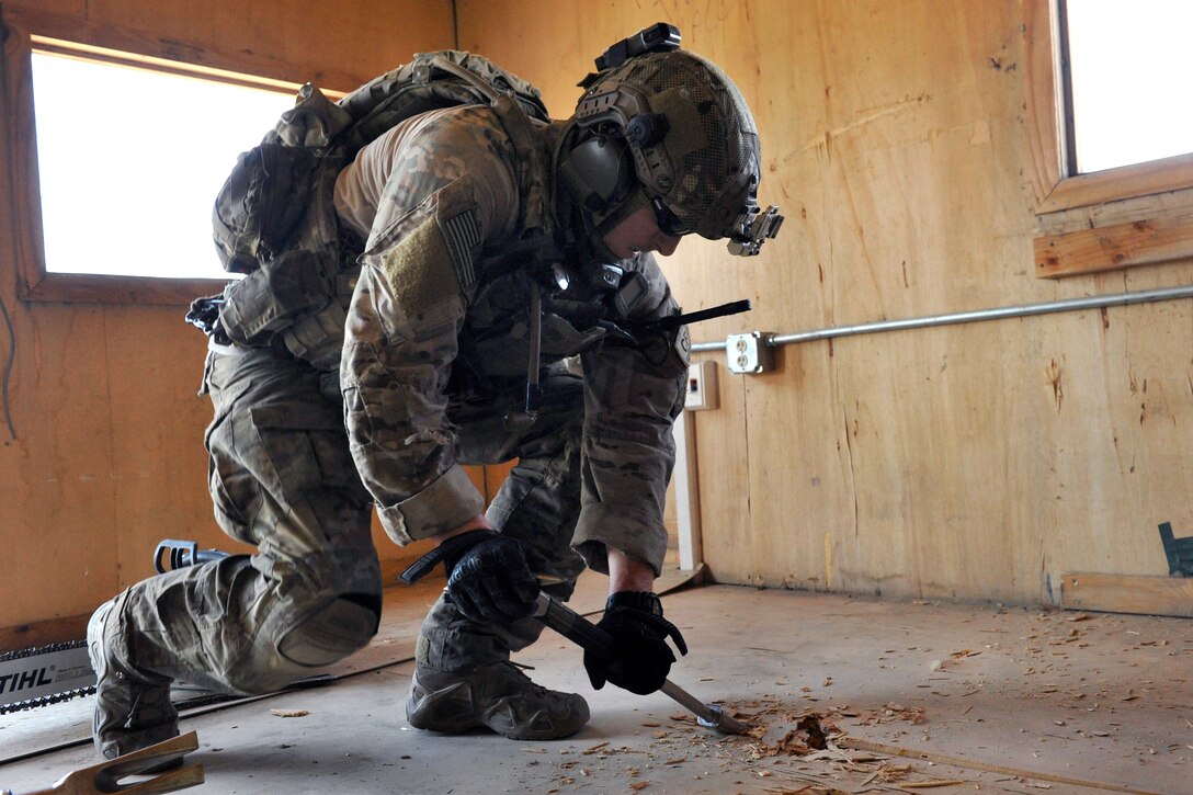 U.S. Air Force Capt. Cameron Rochelle works to cut a hole in the floor during a mission rehearsal on Bagram Airfield, Afghanistan, Aug. 26, 2014. Rochelle is a combat rescue officer assigned to the 83rd Expeditionary Rescue Squadron.