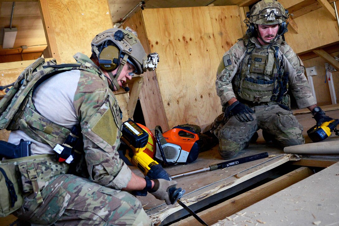 U.S. Air Force Staff Sgt. Jason Lee, left, and U.S. Air Force Senior Airman Thomas Schalin tear boards from a building’s floor and prepare to clear a room during a mission rehearsal on Bagram Airfield, Afghanistan, Aug. 26, 2014. Lee and Schalin are pararescuemen assigned to the 83rd Expeditionary Rescue Squadron.