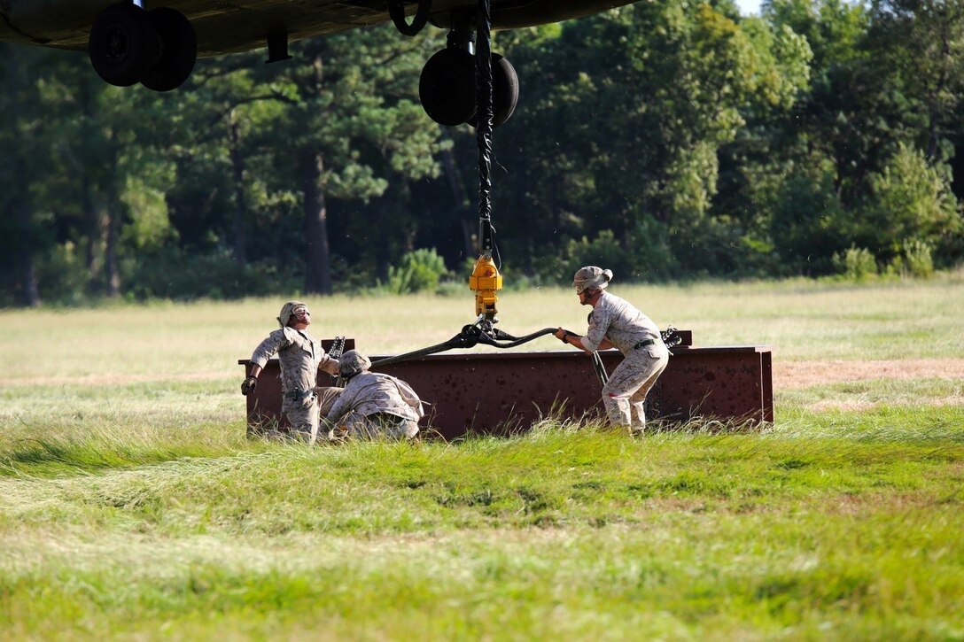 Marines with Combat Logistics Battalion 26, 2nd Marine Logistics Group connect a metal beam to a CH-53E Super Stallion helicopter during external lift training aboard Camp Lejeune, N.C., Aug. 27, 2014. Marines with Helicopter Support Team, CLB-26 partnered with Marine Heavy Helicopter Training Squadron 302, Marine Aircraft Group 29, 2nd Marine Air Wing, to practice single and dual point cargo lifts.