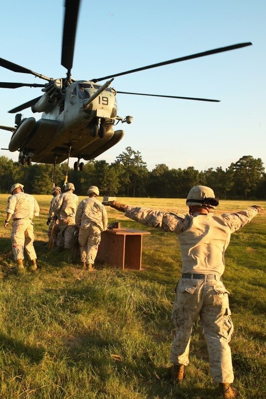 A Marine with Helicopter Support Team, Combat Logistics Battalion 26 guides the pilot of a CH-53E Super Stallion helicopter to successfully extract a metal beam during external lift training aboard Camp Lejeune, N.C., Aug. 27, 2014. Marines with HST, CLB-26 partnered with Marine Heavy Helicopter Training Squadron 302, Marine Aircraft Group 29, 2nd Marine Air Wing, to practice single and dual point cargo lifts.