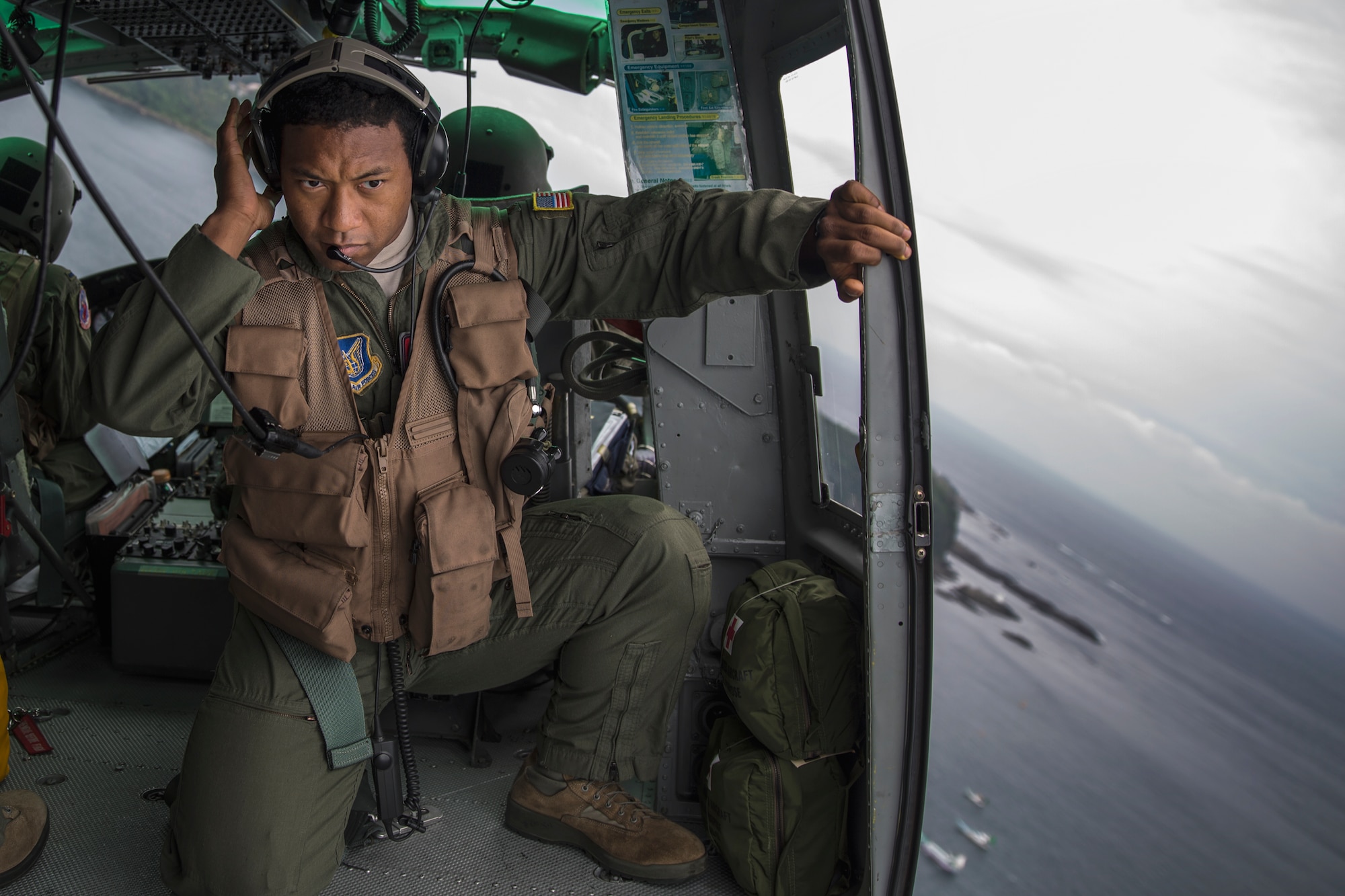 Maj. Zensaku Munn listens to the radio Aug. 31, 2014, during the Shizuoka Comprehensive Disaster Drill over Shimoda bay, Japan. Munn relayed drop clearance to the inbound C-130 Hercules from a UH-1N Iroquois during the drill. Munn is a 374th Operations Support Squadron air mobility liaison officer. (U.S. Air Force photo/Osakabe Yasuo) 