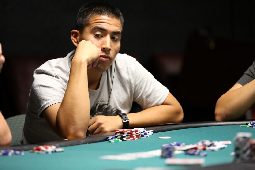 Lance Cpl. Christopher Guzman, student, Company A, Marine Corps Communication-Electronics School, contemplates his next move during the poker tournament sponsored by the Single Marine Program at The Zone, Aug. 28, 2014. The event was open to Marines and sailors stationed at the Combat Center.


