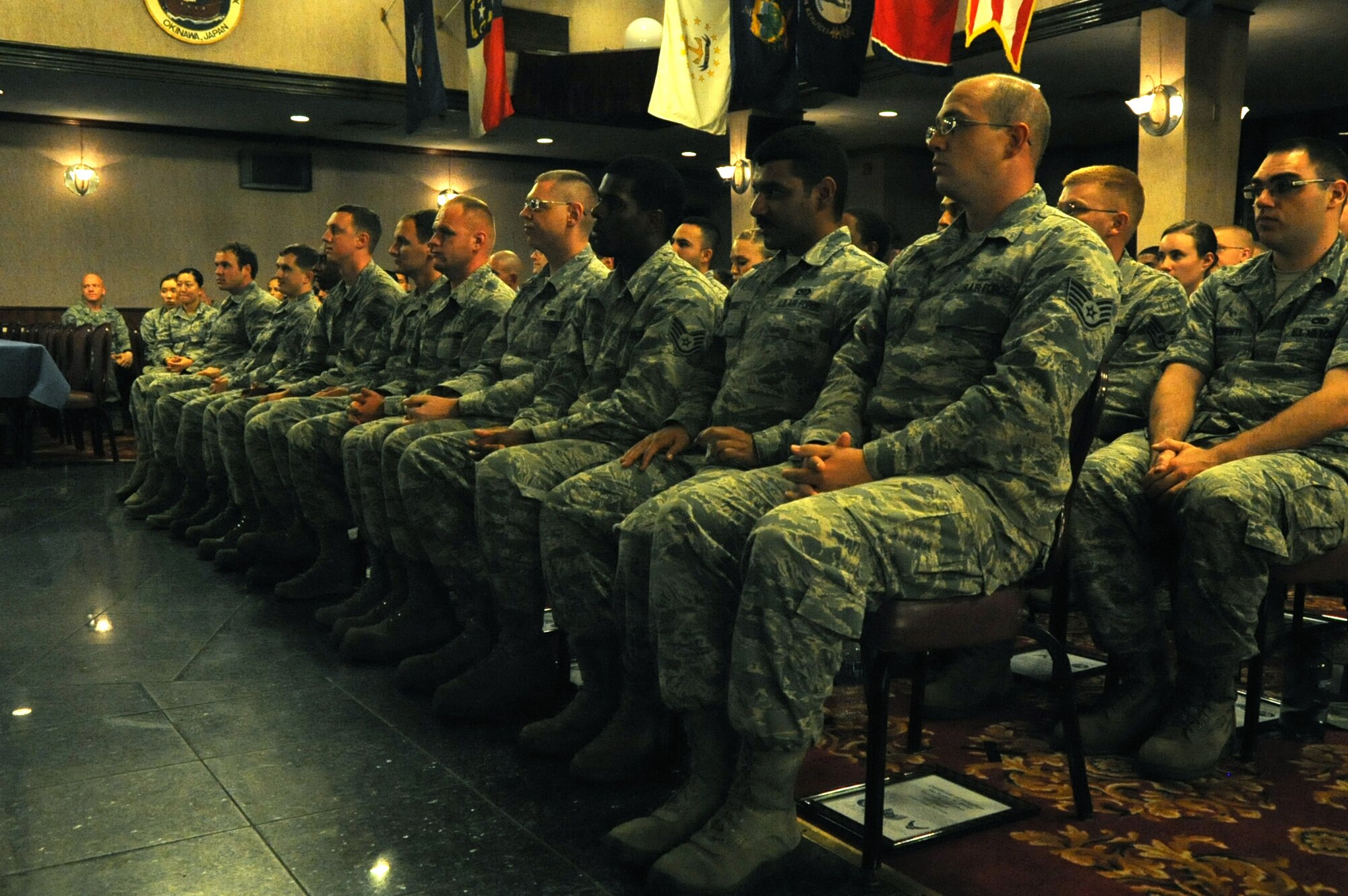 After receiving their framed certificates, the newly inducted NCOs listen to a speech during an NCO induction ceremony at the Rocker NCO club, Kadena Air Base, Japan, Sept. 3 2014. The ceremony celebrates and recognizes those who have recently put on the rank of staff sergeant and have reached the status of NCO. (U.S. Air Force photo by Airman 1st Class Zackary A. Henry/Released)