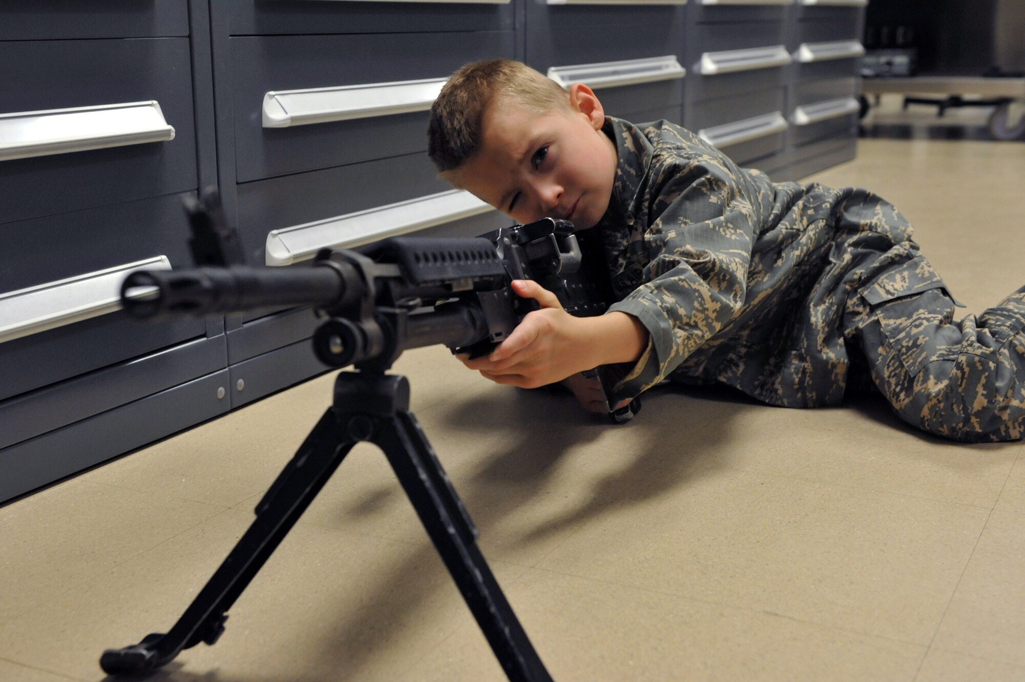 Keegan Stipe, left, a 7-year-old boy who is overcoming transverse myelitis, a spinal condition that limits his ability to walk, gets to feel what it’s like to hold a M240b light machine gun during his Airman for a Day base tour Aug. 26, 2014, on Buckley Air Force Base, Colo. Keegan has always been fascinated with fast planes, loud guns and the military lifestyle, so the 460th Space Wing gave him and his parents the opportunity to visit the base. On his tour, he visited the 140th Wing, Air National Guard and various 460th SFS sections. (U.S. Air Force photo by Airman Emily E. Amyotte/Released)