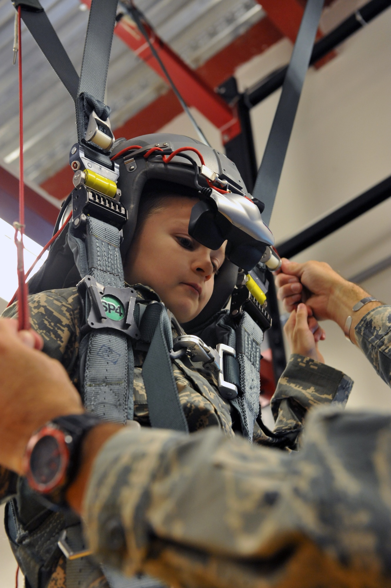 Keegan Stipe, left, a 7-year-old boy who is overcoming transverse myelitis, a spinal condition that limits his ability to walk, simulates landing a parachute during his Airman for a Day base tour Aug. 26, 2014, on Buckley Air Force Base, Colo. Keegan has always been fascinated with fast planes, loud guns and the military lifestyle, so the 460th Space Wing gave him and his parents the opportunity to visit the base. On his tour, he visited the 140th Wing, Air National Guard and various 460th SFS sections. (U.S. Air Force photo by Airman Emily E. Amyotte/Released)