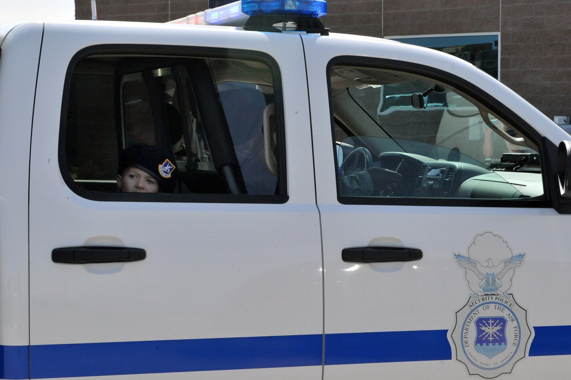 Keegan Stipe, left, a 7-year-old boy who is overcoming transverse myelitis, a spinal condition that limits his ability to walk, gets escorted in the back of a security forces squad car during his Airman for a Day base tour Aug. 26, 2014, on Buckley Air Force Base, Colo. Keegan has always been fascinated with fast planes, loud guns and the military lifestyle, so the 460th Space Wing gave him and his parents the opportunity to visit the base. On his tour, he visited the 140th Wing, Air National Guard and various 460th SFS sections. (U.S. Air Force photo by Airman Emily E. Amyotte/Released)
