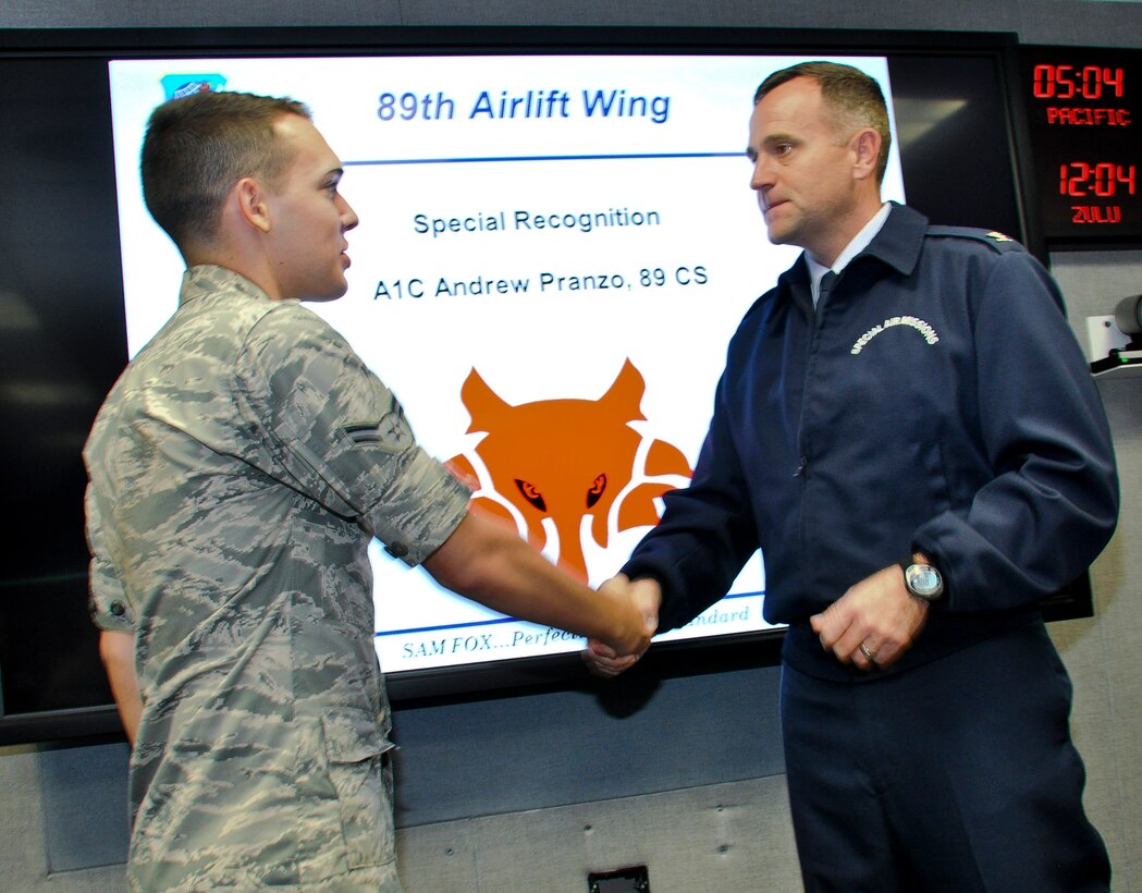 Airman 1st Class Andrew Pranzo, 89th Communications Squadron airborne communications technician, is coined by Col. John C. Millard, 89th Airlift Wing commander, during a special recognition ceremony at Joint Base Andrews, Md., Sept. 3, 2014. Pranzo, a 19-year-old Las Vegas native has been in the Air Force merely nine months, yet used his basic military training self-aid and buddy care techniques to bandage an injured man’s head after witnessing the man fall about four feet and smash his head on a boulder about two miles into the mountains at Shenandoah National Park, Va., Aug. 10. The fall caused a Y-shaped gash in the man’s forehead from hair-line to eyebrow, which exposed his skull. (U.S. Air Force photo by Master Sgt. Kevin Wallace/RELEASED)