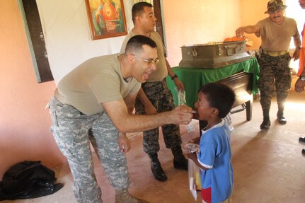 U.S. Army Capt. Manuel Bucardo coaxes a Honduran child to take de-wormer medication during a medical readiness training exercise Aug. 25-28 in the remote village of Rio Platano, Department of Gracias a Dios, Honduras.  MEDEL partnered with the Honduran Ministry of Health and the Honduran military to provide classes for the patients to teach them about hygiene, nutrition, and preventative dental practices.  They also provide wellness checkups, medication, dental care, and perform minor medical procedures as required.  (Photo by U.S. Army Spec. Anthony Gonzales)